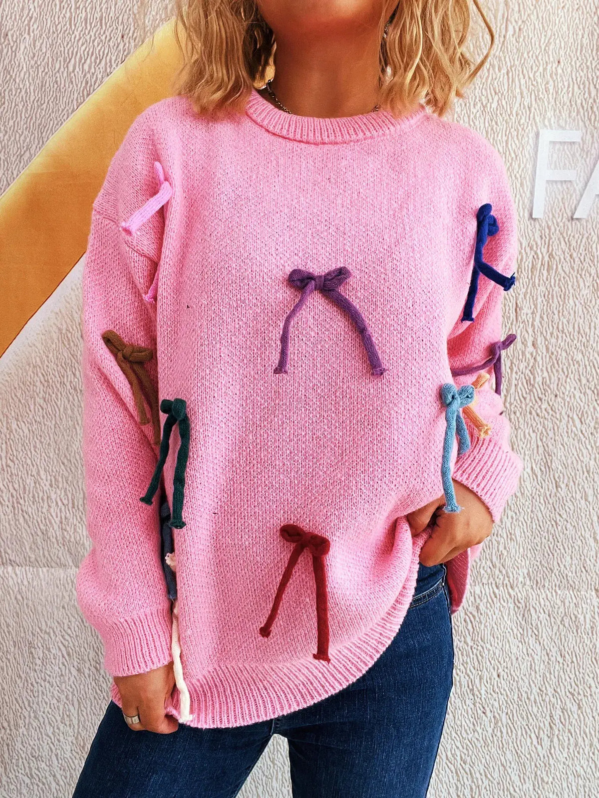 Pink knit round-neck pullover sweater with multicolor bow accents
