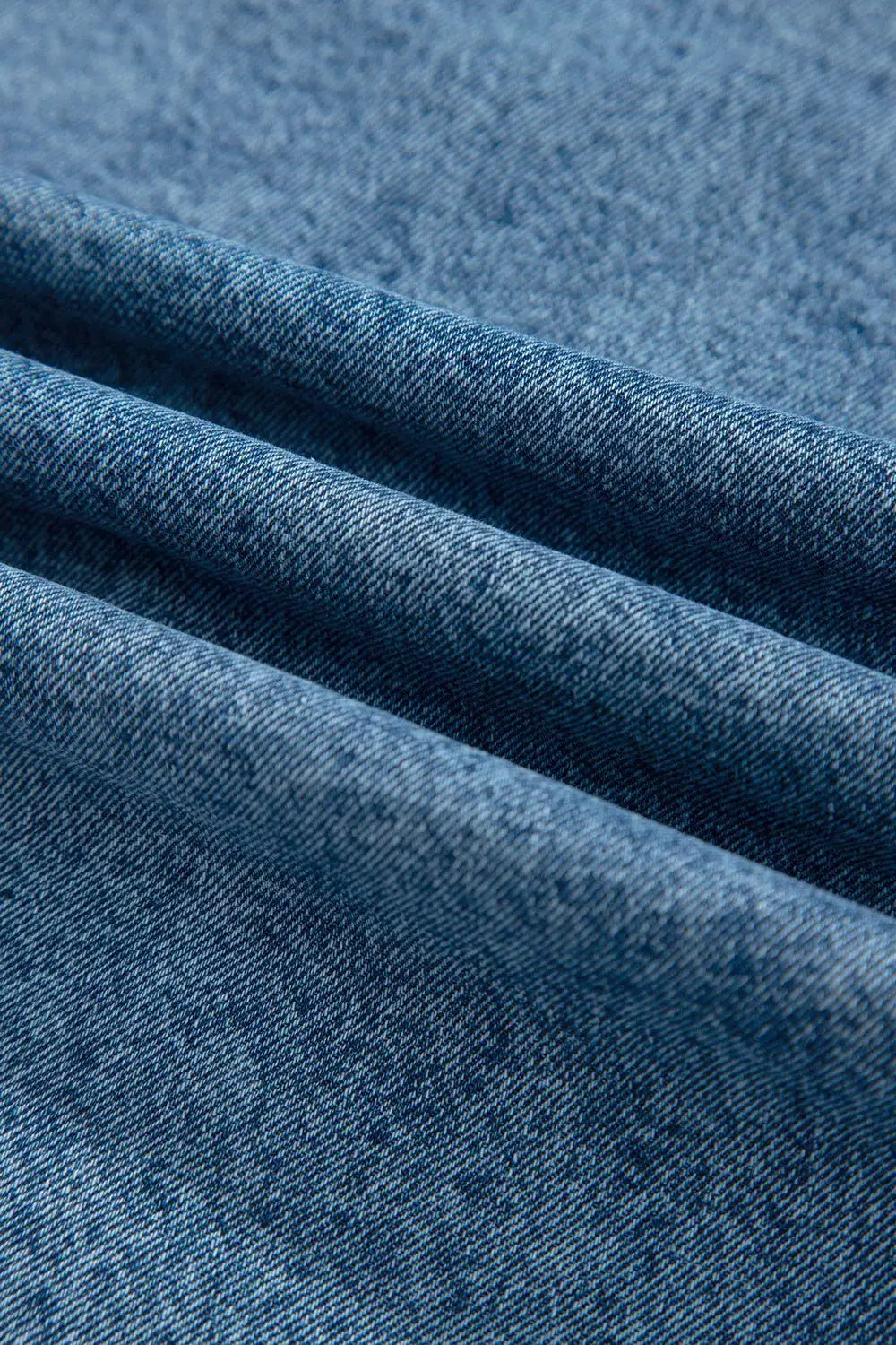 Blue denim jacket fabric close-up; textured cotton denim