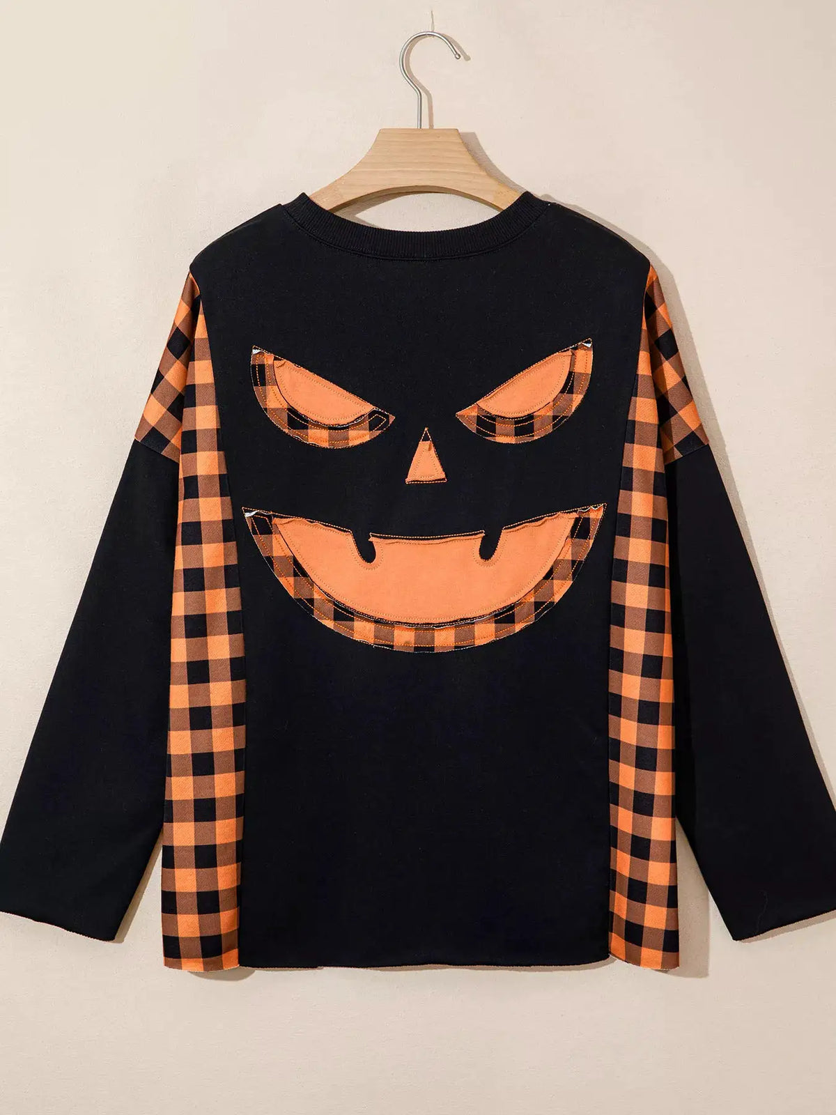 Patchwork Plaid Pumpkin Face Long Sleeve Top by Trendsi; black knit with orange plaid sleeves and pumpkin face patch