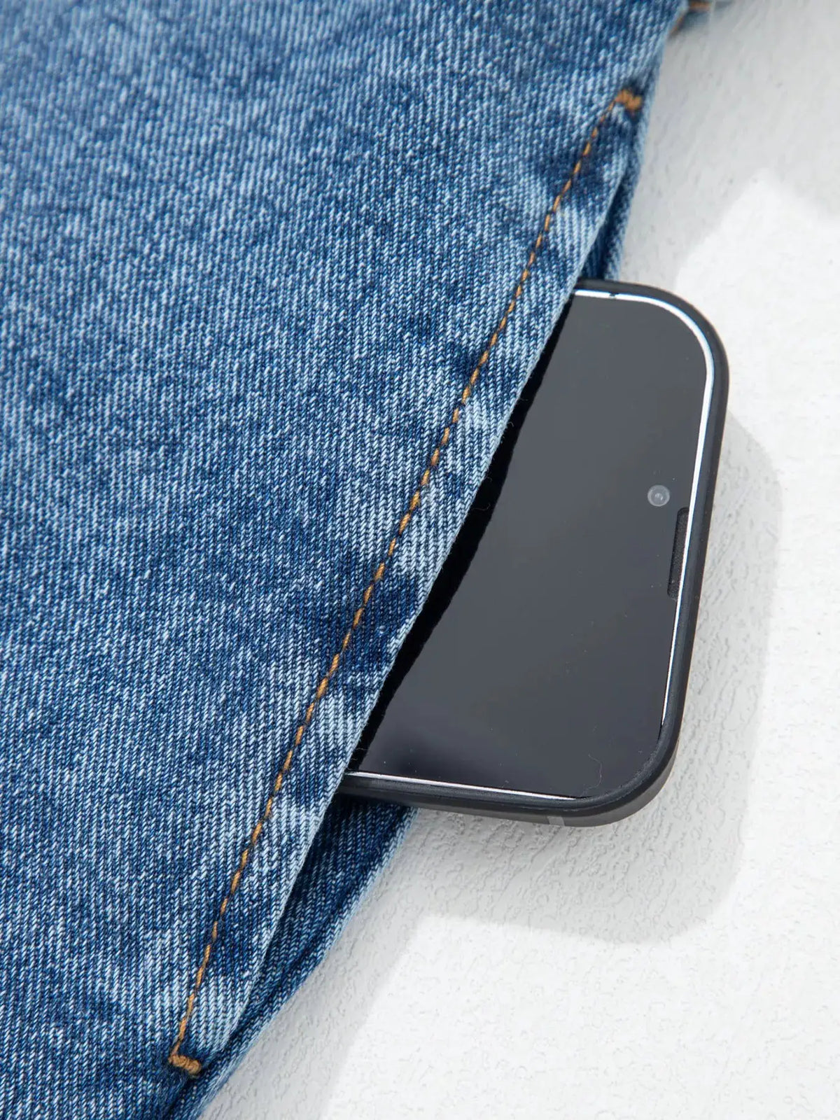 Slim fit button-front denim vest in blue; close-up of textured fabric with a smartphone peeking from edge