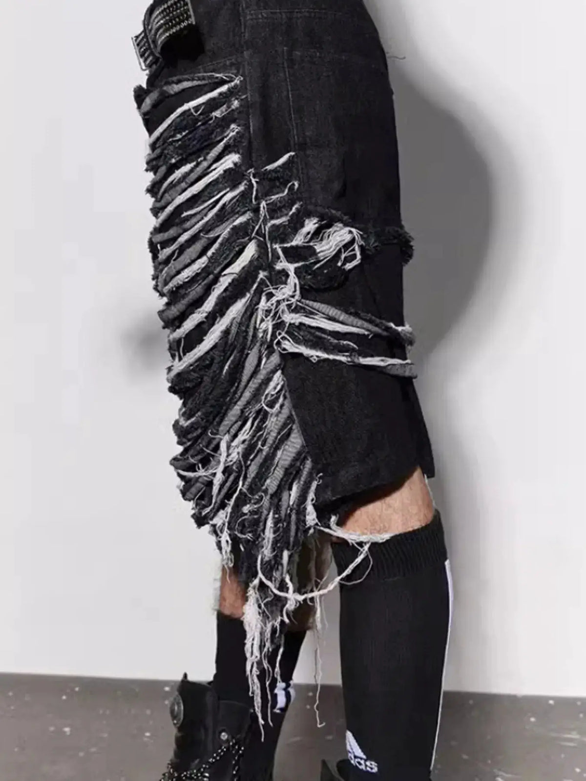 Men's black denim shorts with frayed hems and white fringe along the sides.