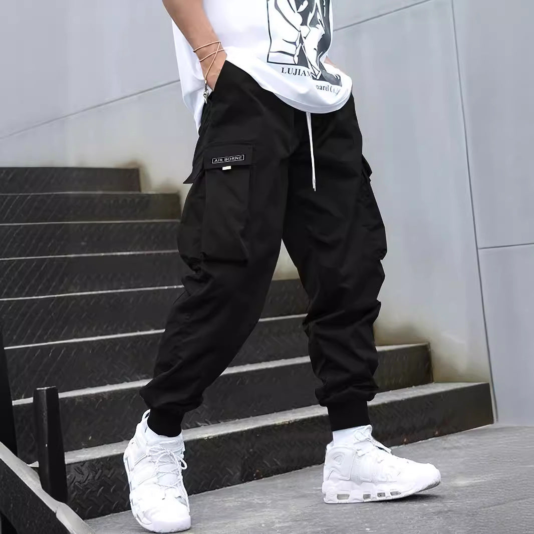 Men's black cargo pants with multiple pockets and drawstring waist, elastic cuffs at the ankles
