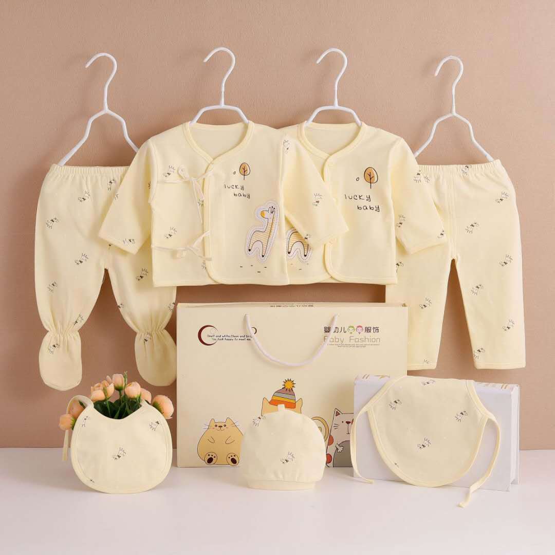 Seven-piece newborn clothing set in pale yellow, includes jackets, pants, hat, bib, and accessories
