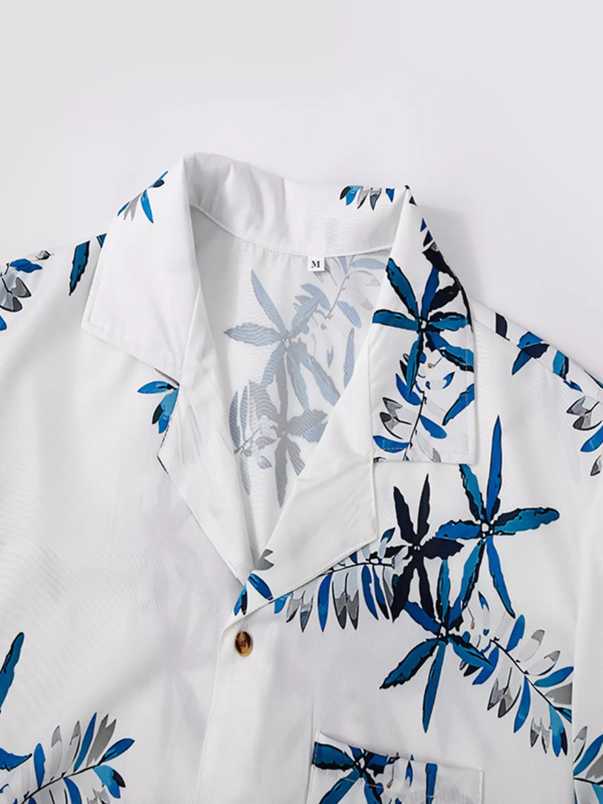 Men's tropical print short sleeve shirt from Trendsi, white with blue leaf pattern, buttoned front with pocket