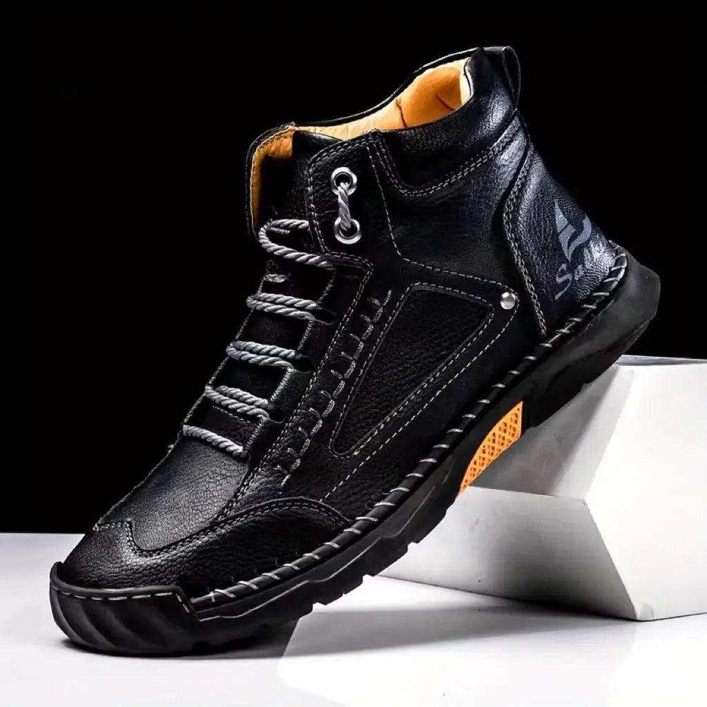 Aveline black leather ankle boots with comfort flat heel, white stitching, rugged sole and orange outsole accent.