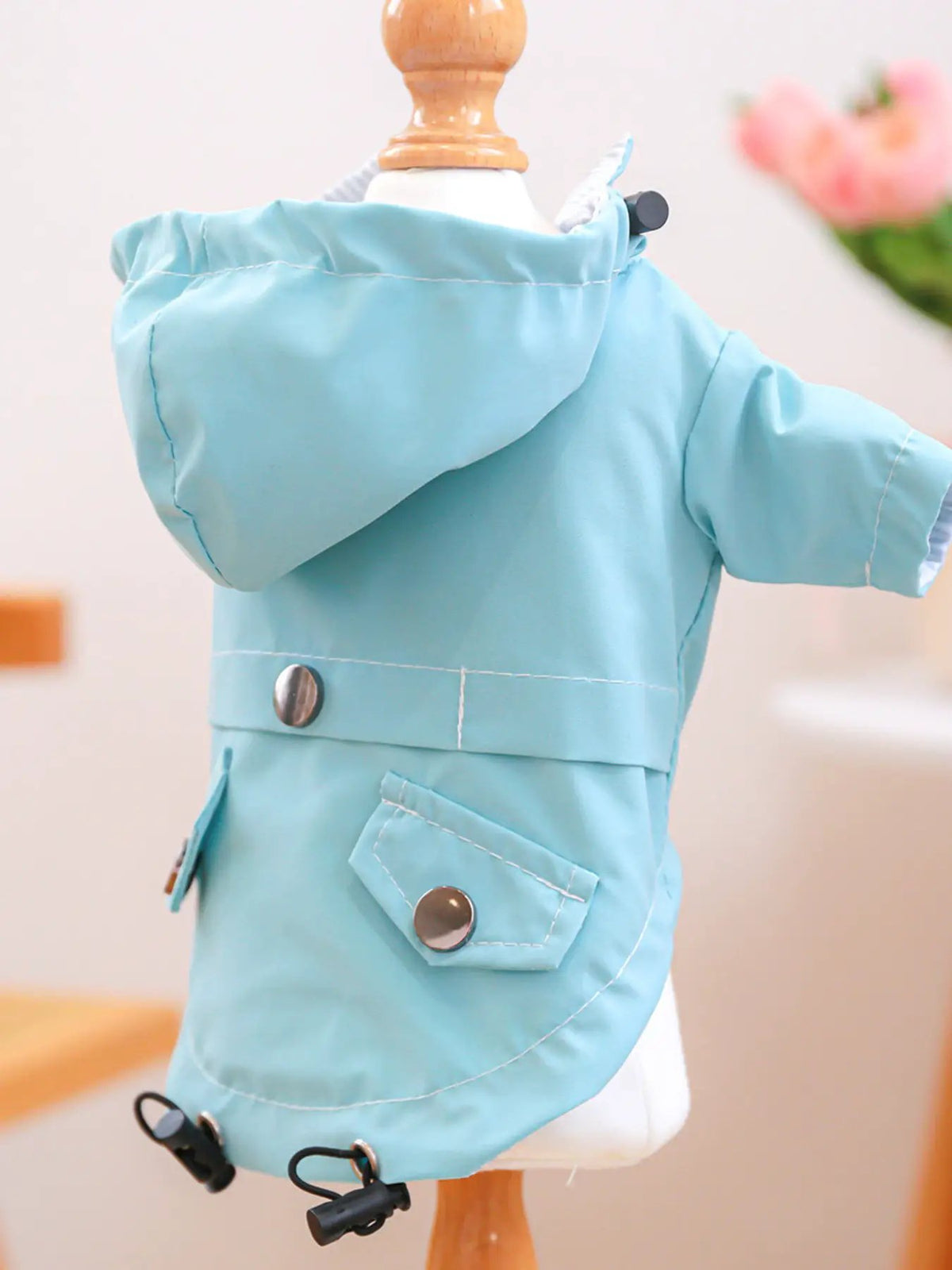 Lightweight waterproof pet raincoat in turquoise blue, hooded with metal snaps and a front pocket.