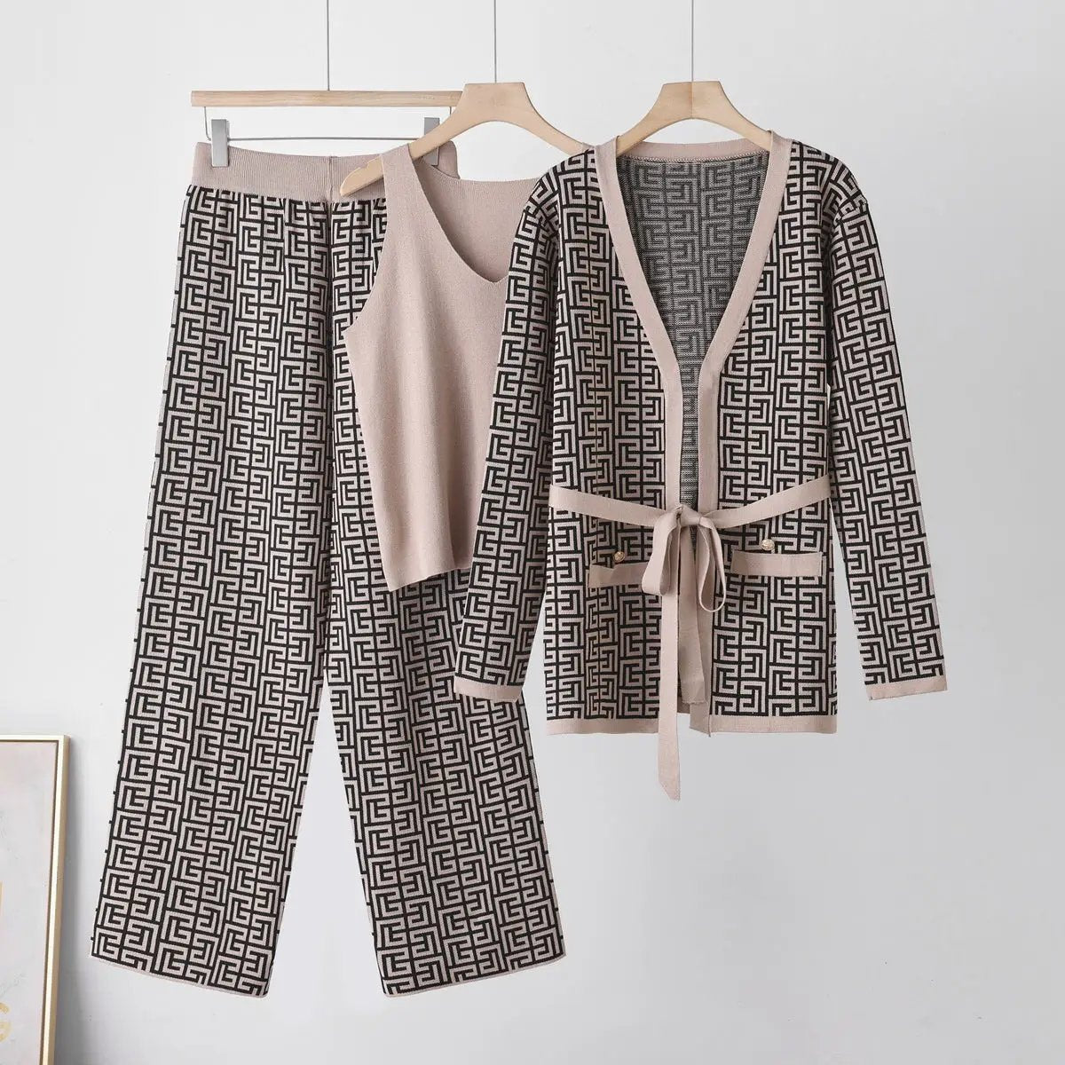Three-piece knit set with beige sleeveless top, belted cardigan, and matching black-and-beige geometric pants