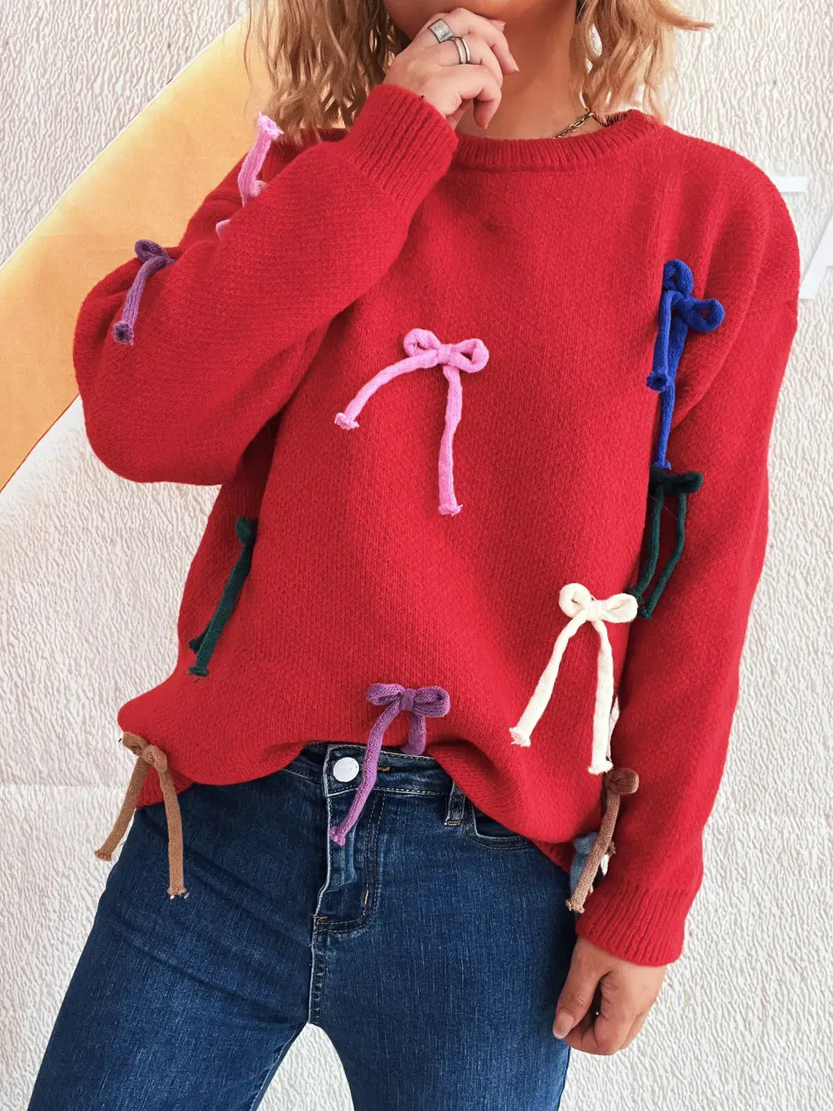 Vibrant bow-accents round-neck women's sweater in red knit with multicolor bows along sleeves and front.