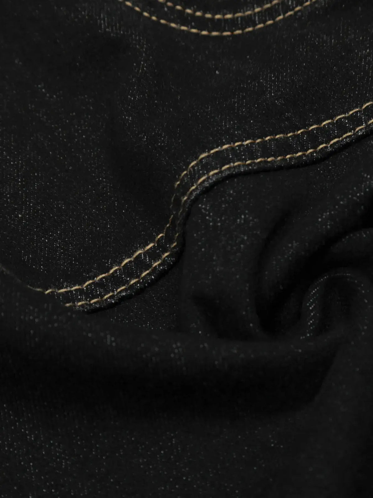 Mens wide-leg cotton denim shorts close-up in black fabric with tan contrast stitching along pocket seam