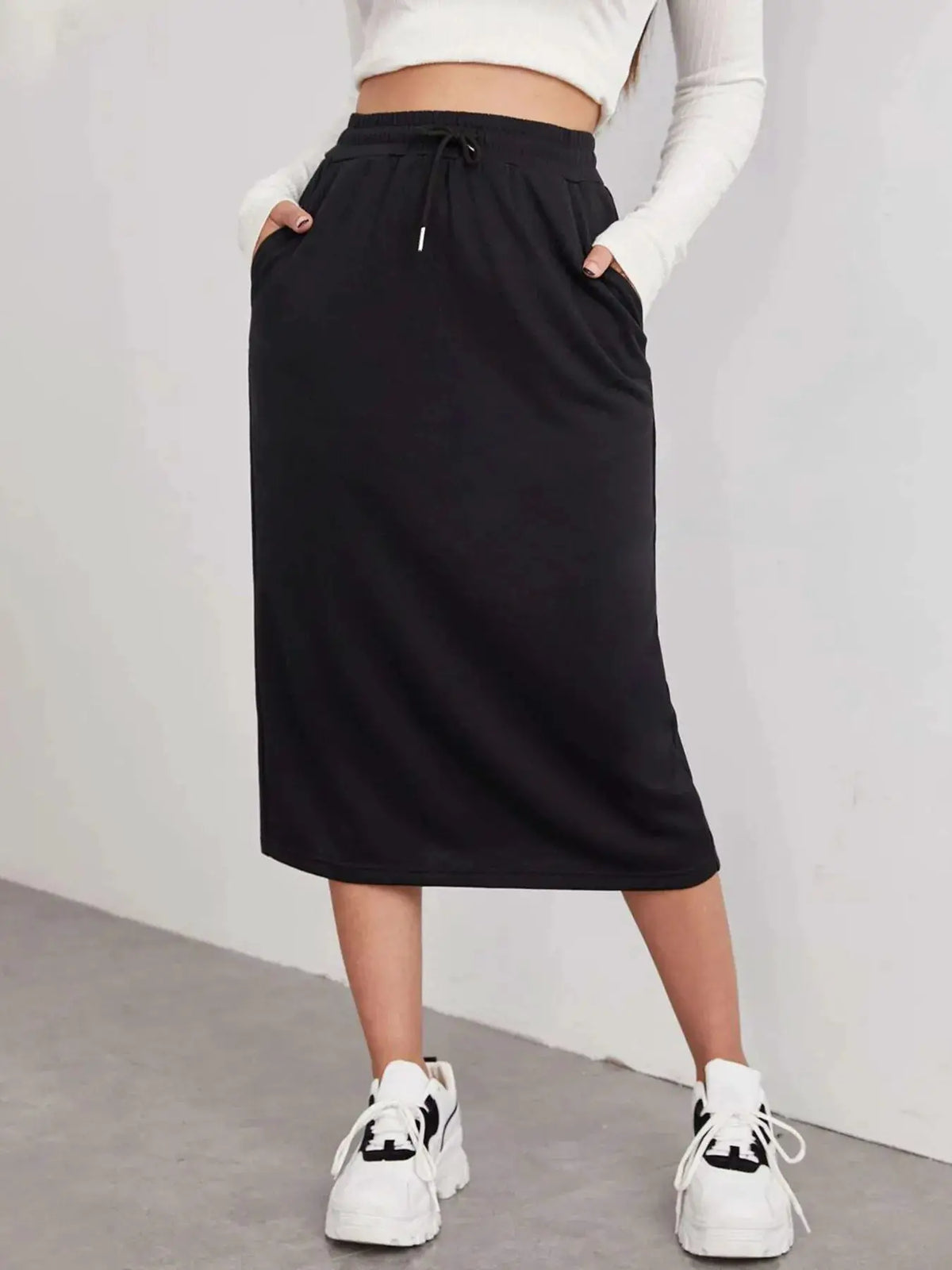 Slit drawstring midi skirt in black, paired with a white cropped top and sneakers