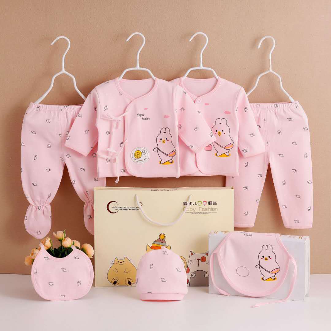 Seven-piece pink newborn clothing set by AdTec with bunny-print tops, pants, hats, and bibs
