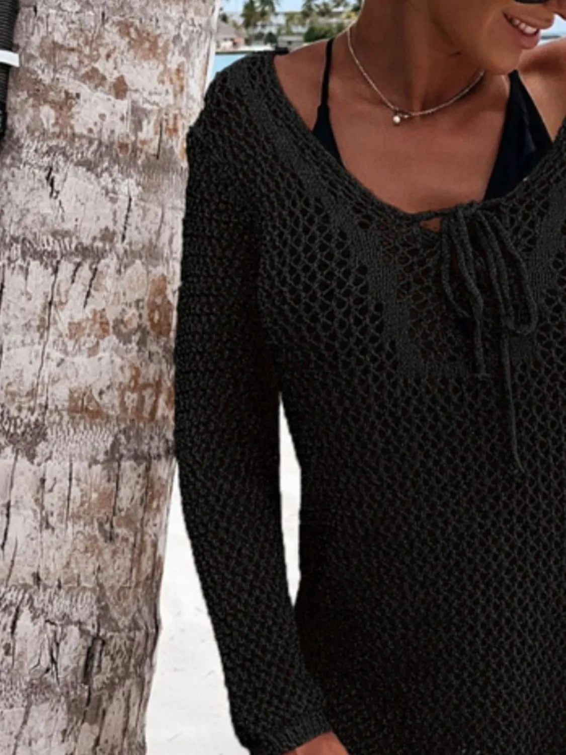 Sheer openwork long-sleeve knit cover-up in black worn over a bikini top.