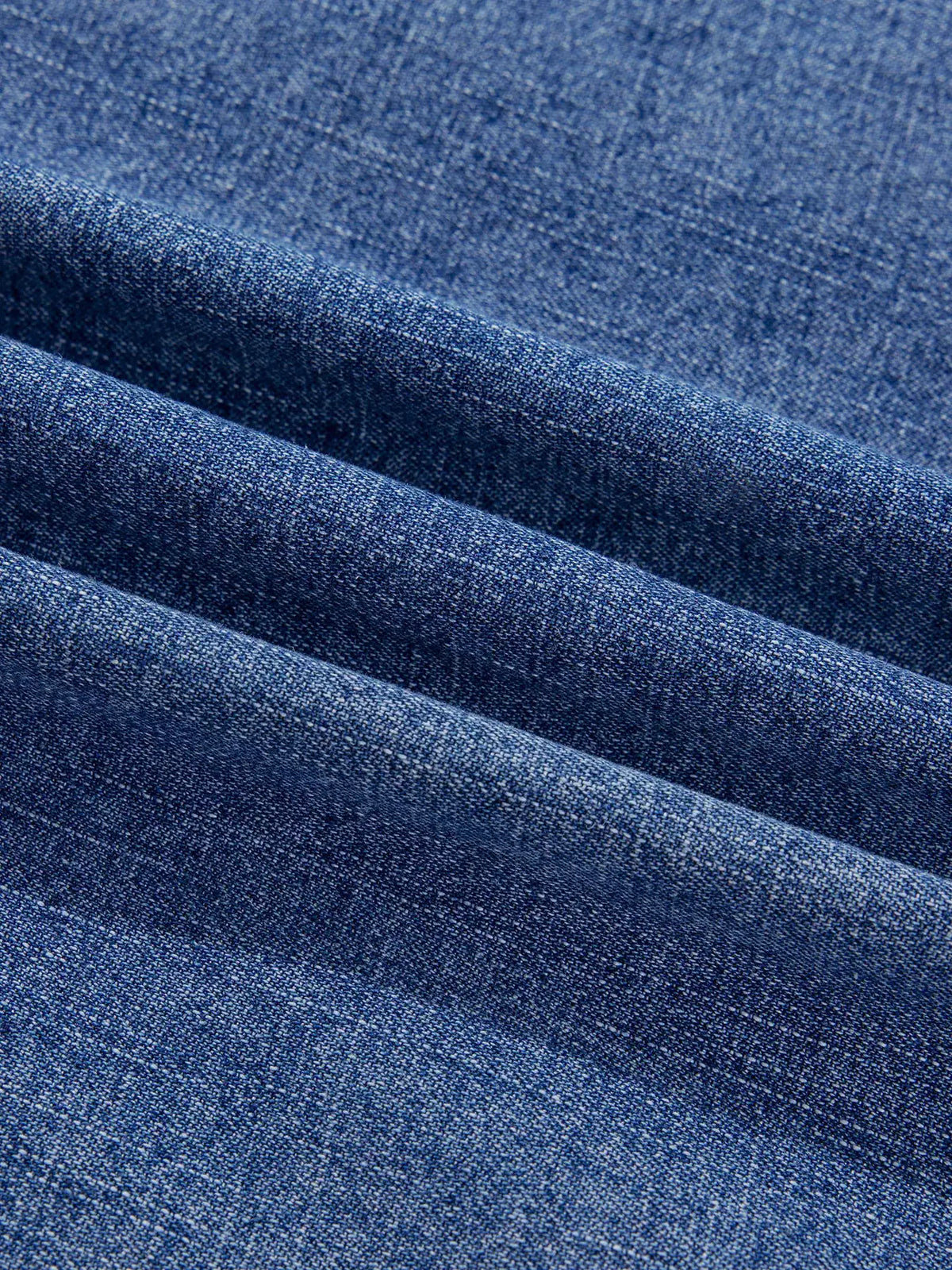 Relaxed denim shirt fabric close-up in blue with visible weave.