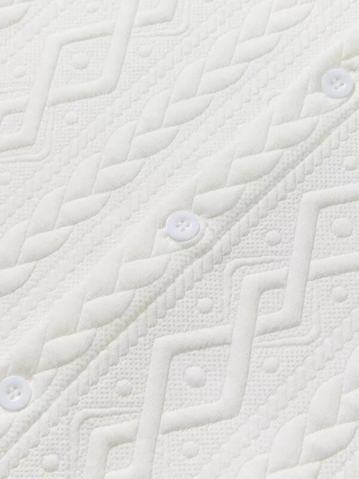 Men's white textured knit polo fabric close-up with buttons
