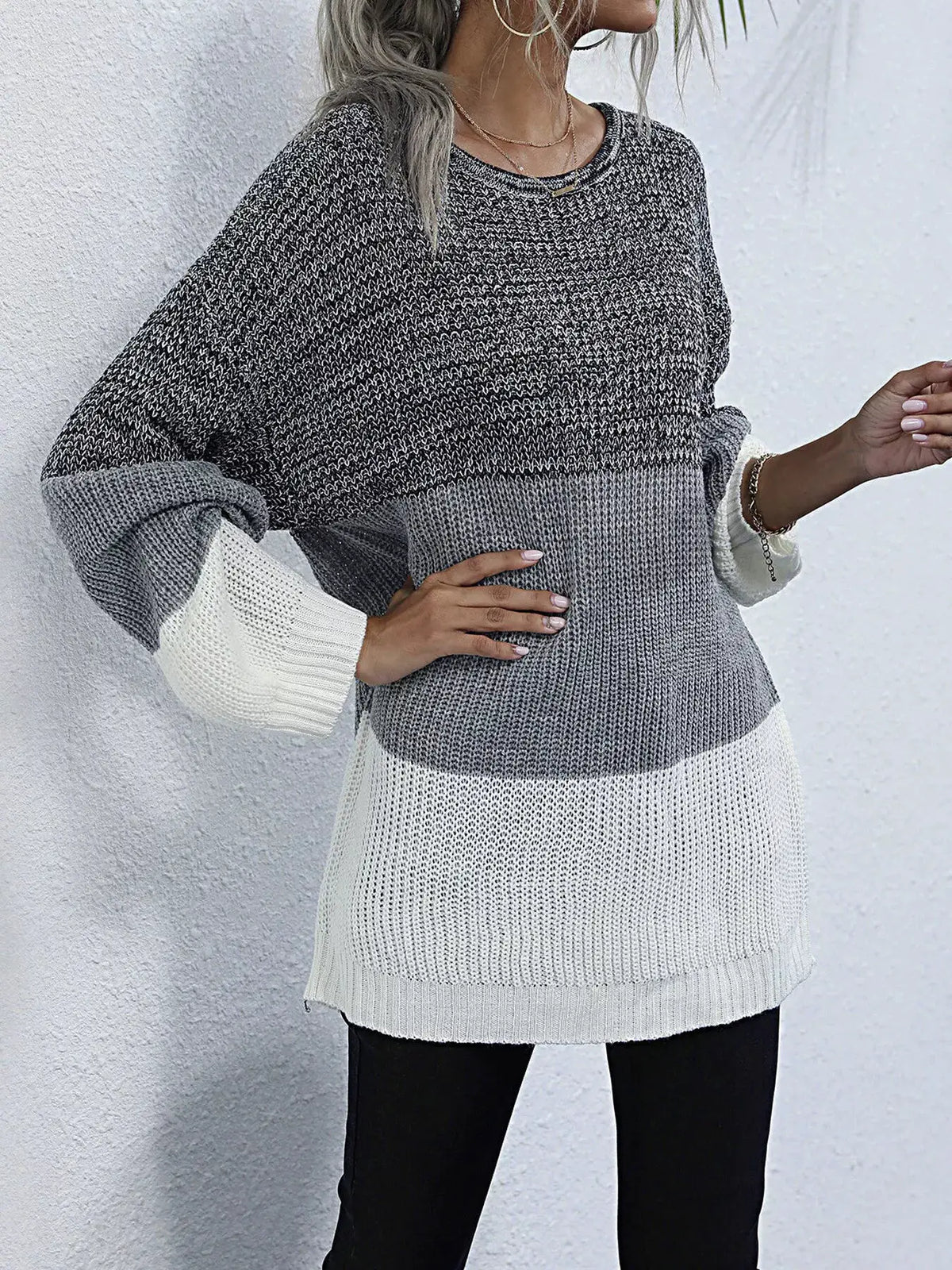 Color-blocked oversized knit sweater with charcoal to light gray gradient and white hem, round neck.