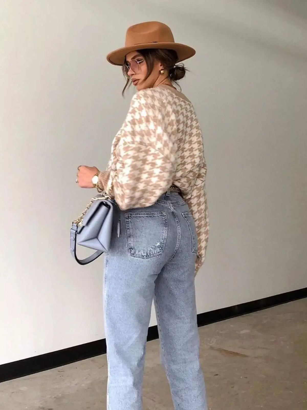 Classic oversized houndstooth sweater in cream beige with light-wash jeans and a tan hat.