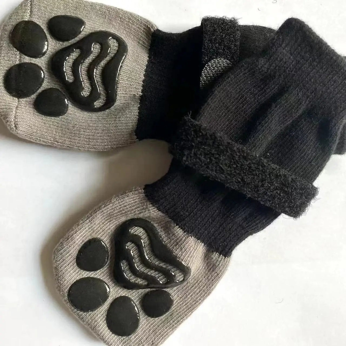 Pair of beige pet sock shoes with black non-slip paw-print soles and black cuffs