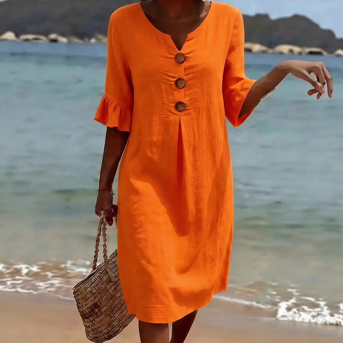 Summer Women’s solid colored cotton dress in orange with three large brown buttons and ruffled sleeves.