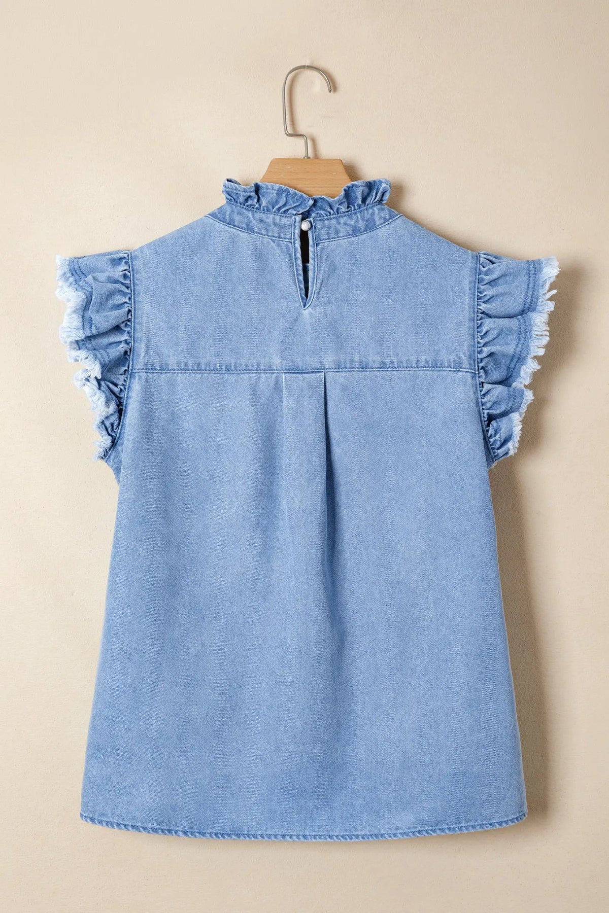 Light blue denim top with frill collar and wide flutter sleeves on a wooden hanger