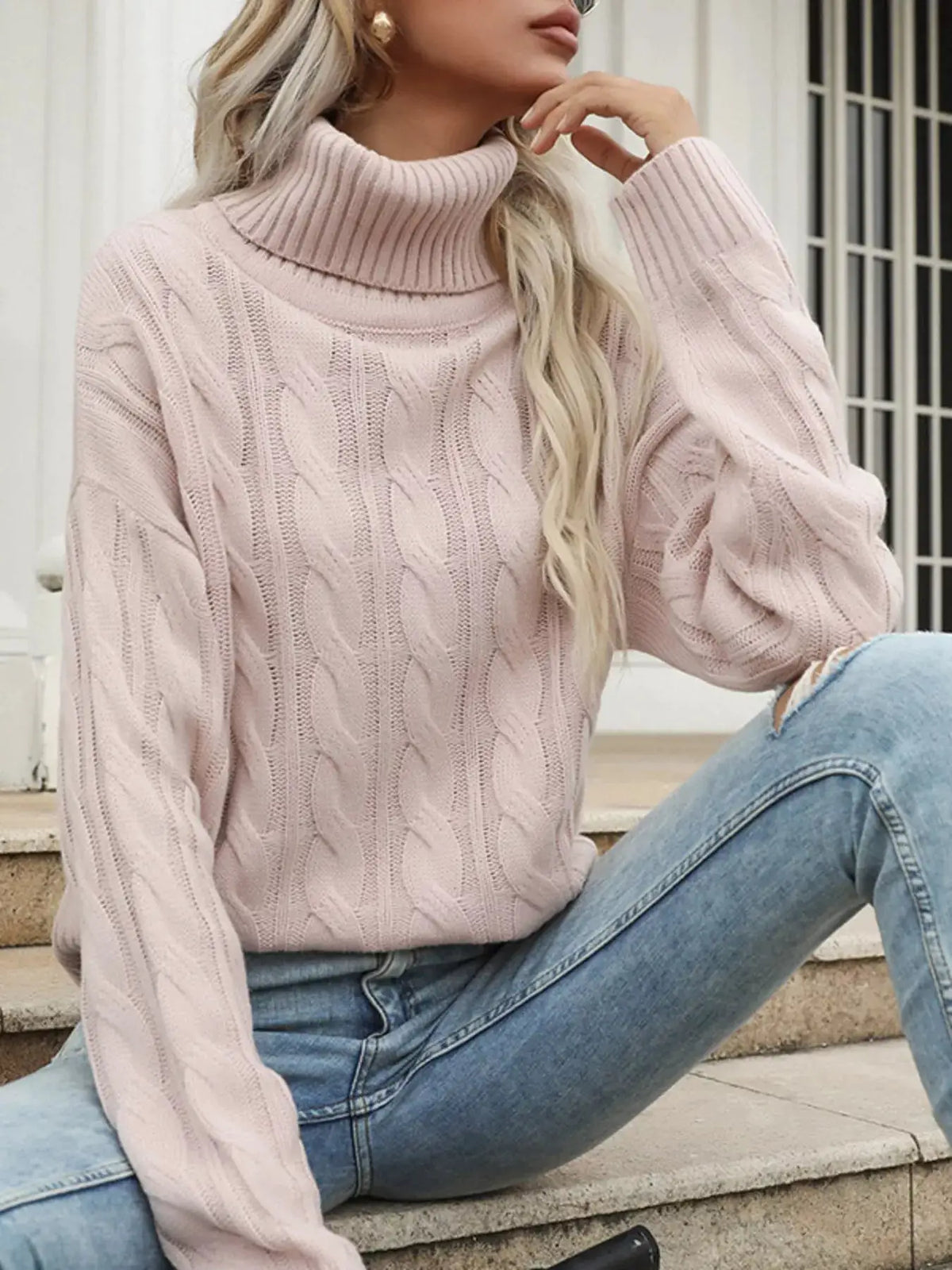 Cozy cable-knit turtleneck sweater in soft pink with a chunky knit texture