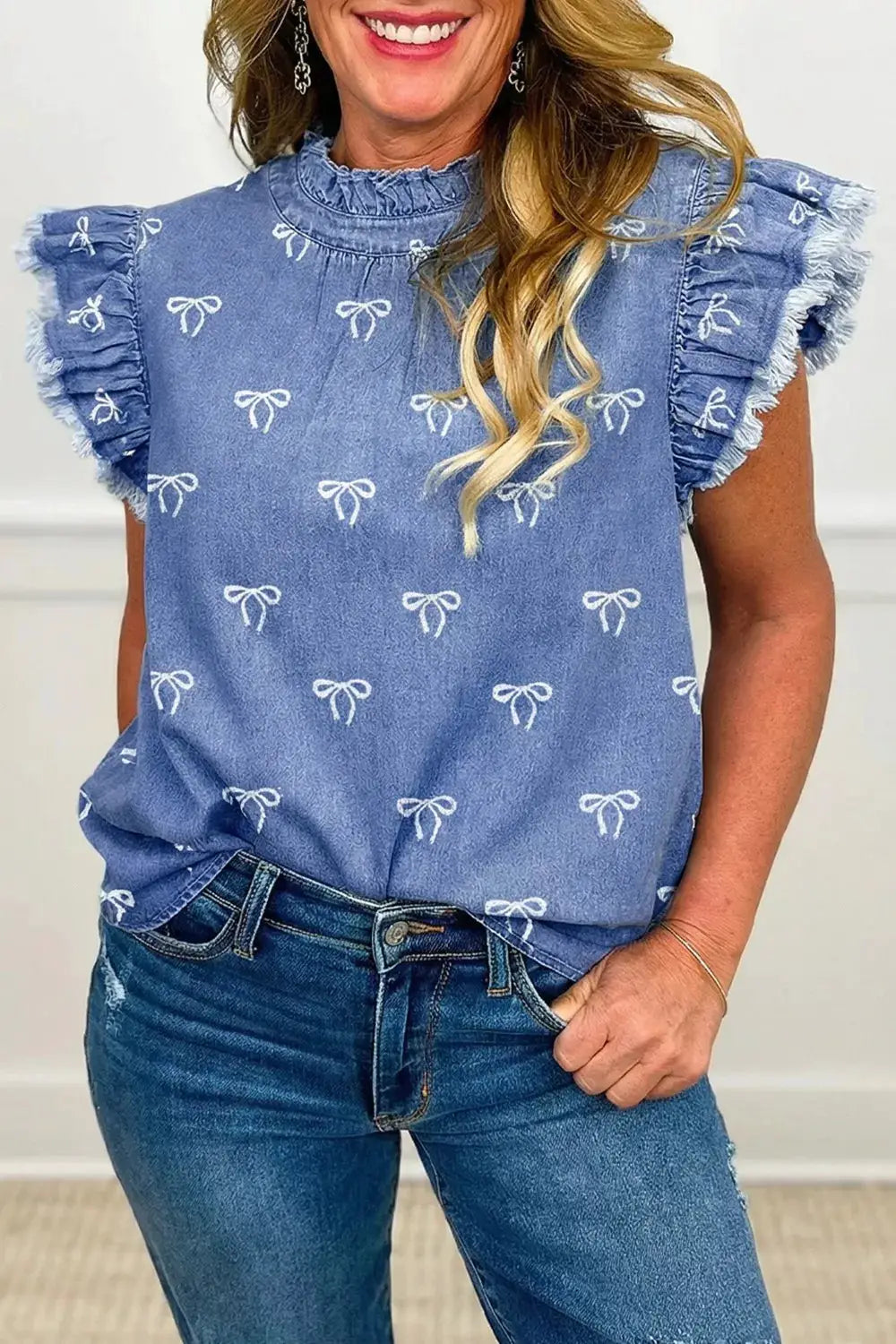 Denim top with frilled collar and flutter sleeves, blue wash with white bow print and raw-hem finish