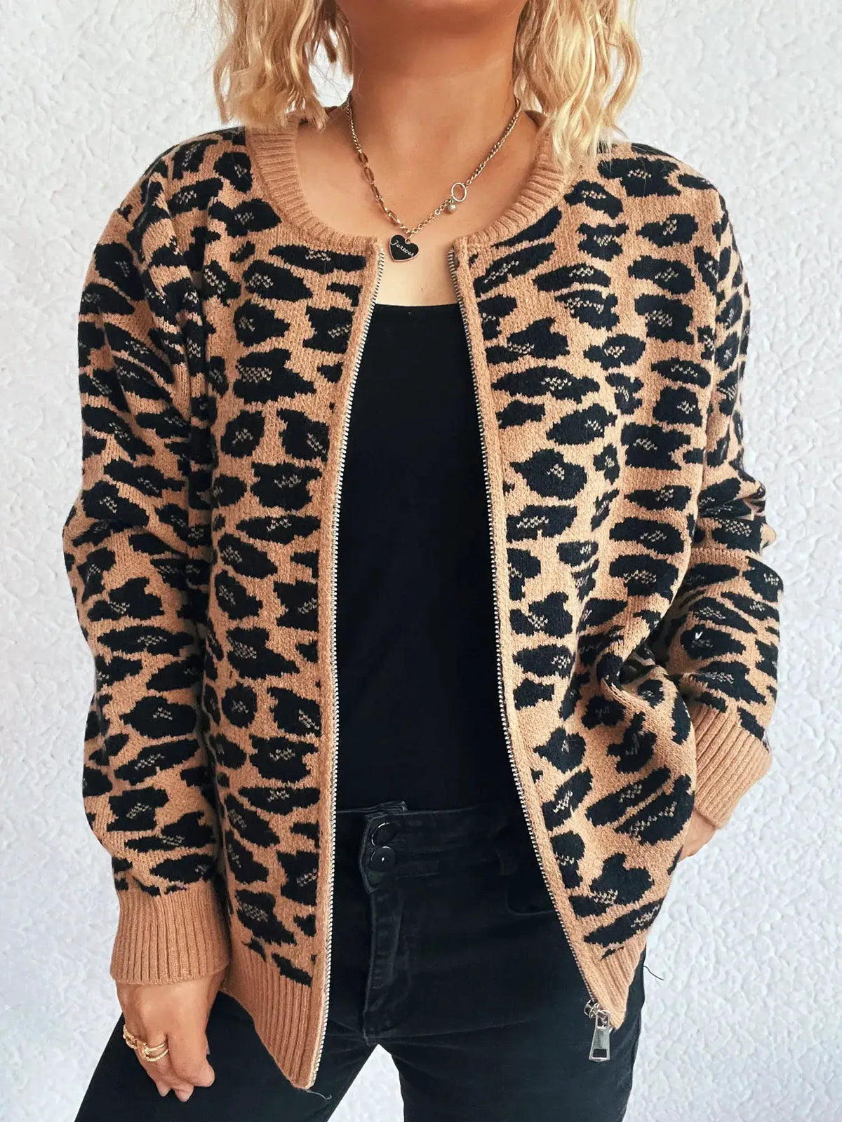 Zip-up long sleeve leopard print cardigan in tan and black with ribbed cuffs and hem, worn over black top.