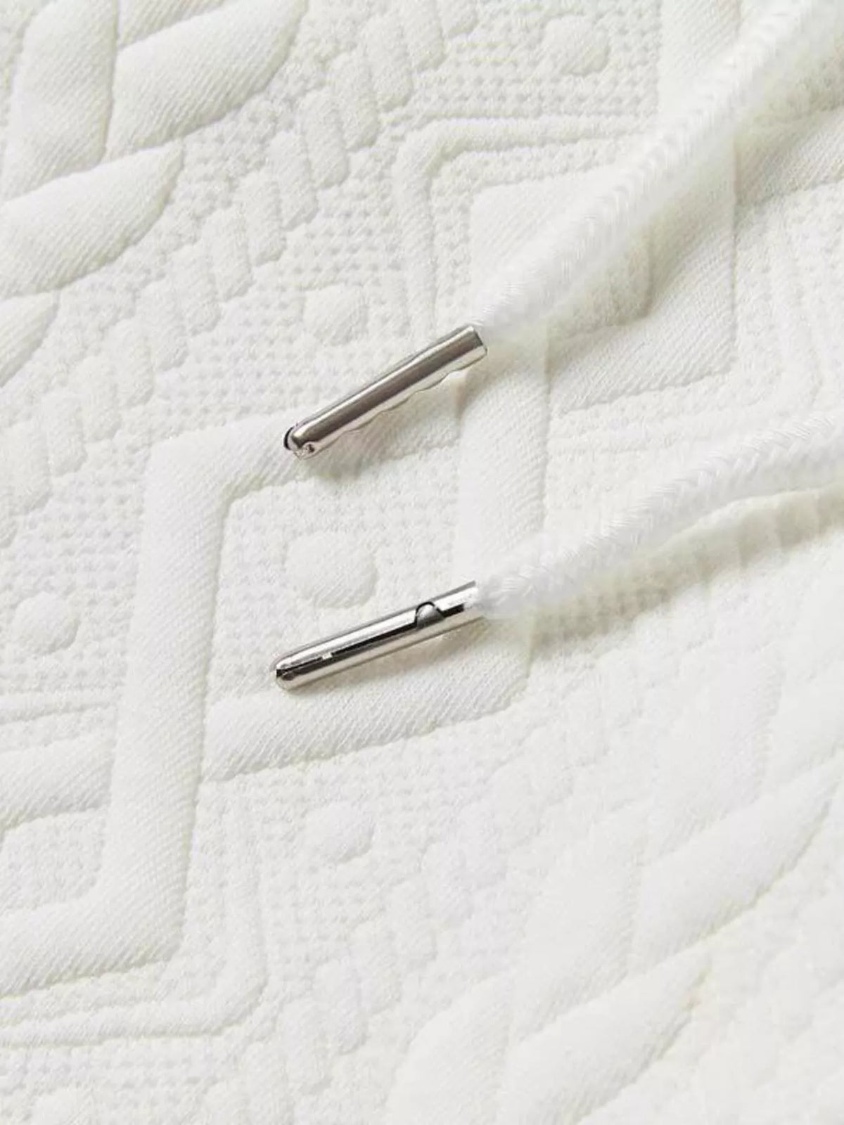 Men's textured knit polo and shorts set on white quilt; two small silver metal tubes visible.