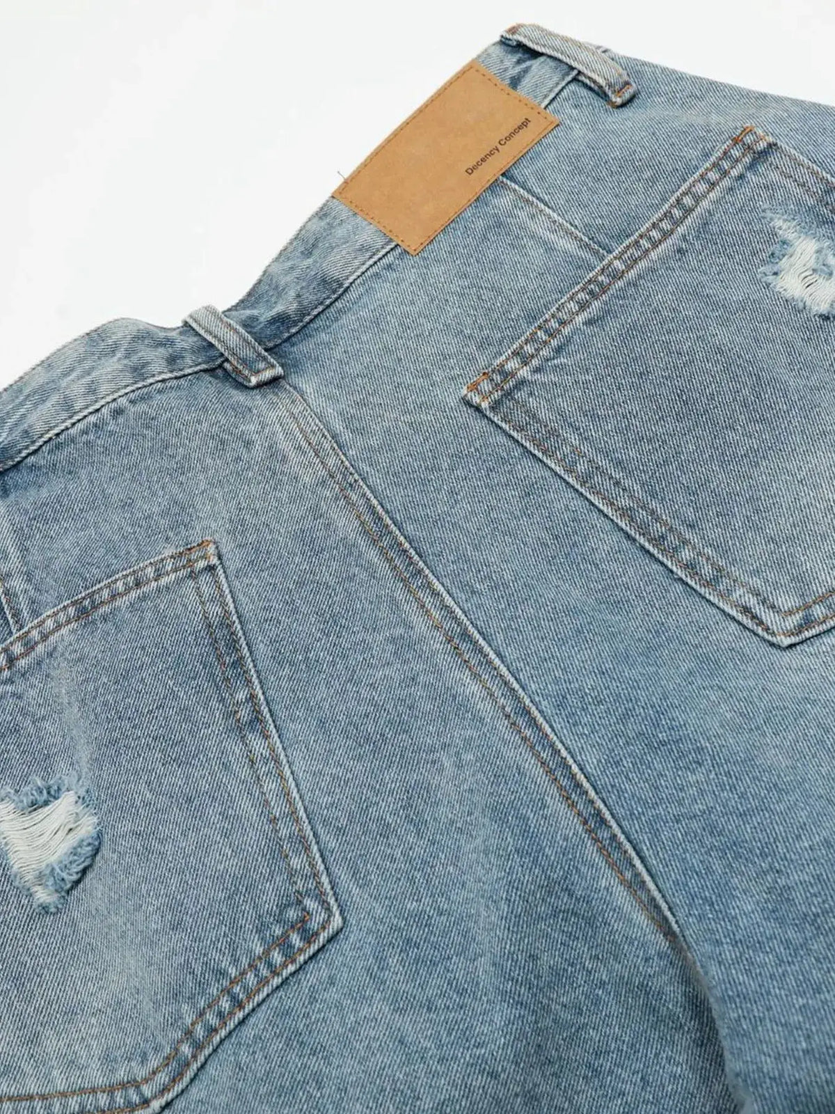 Mens oversized distressed denim shorts in light blue cotton blend with belt loops and tan patch on back waistband