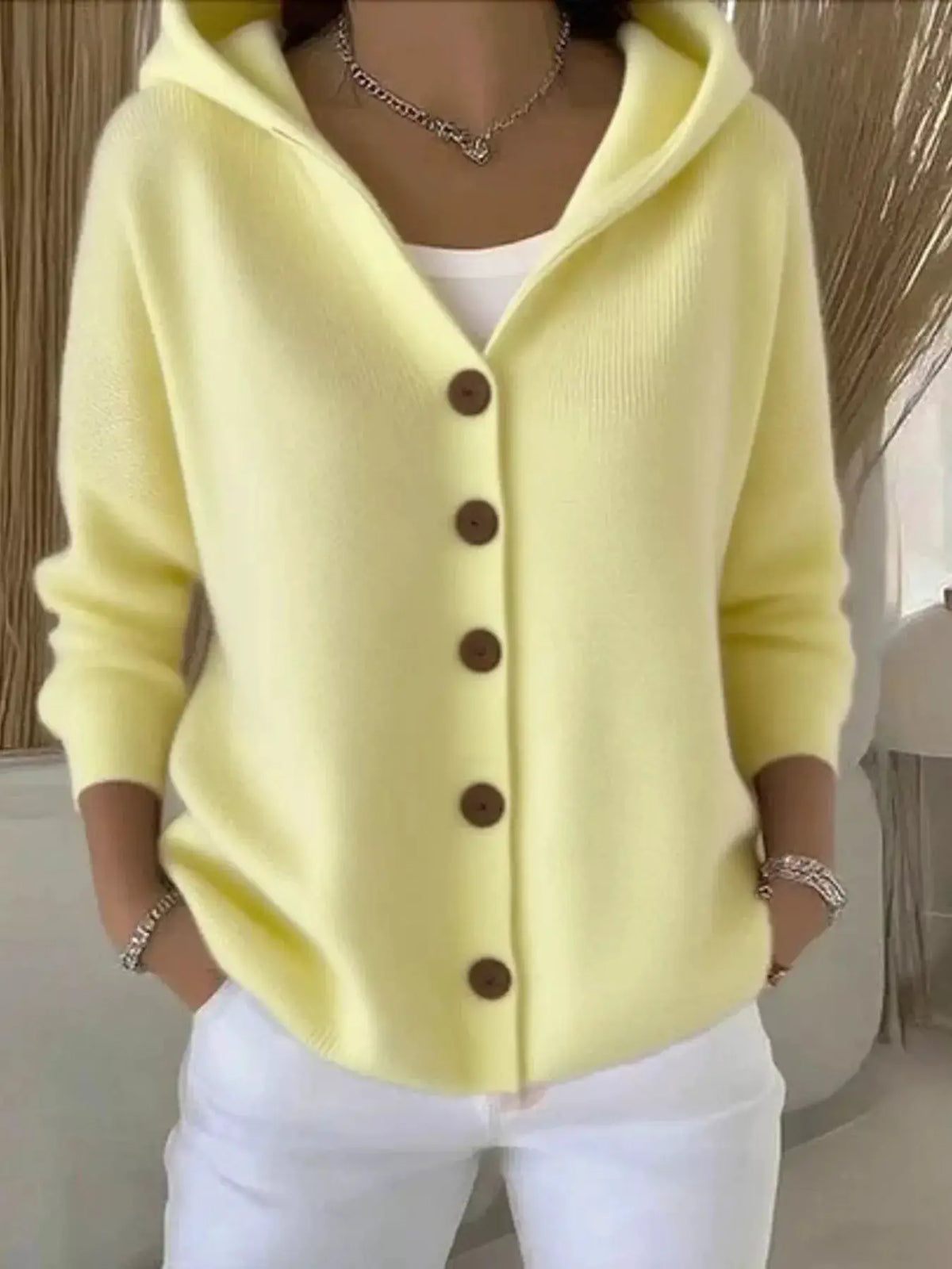 Plus-size hooded knit cardigan with front buttons in pale yellow, worn over a white top.
