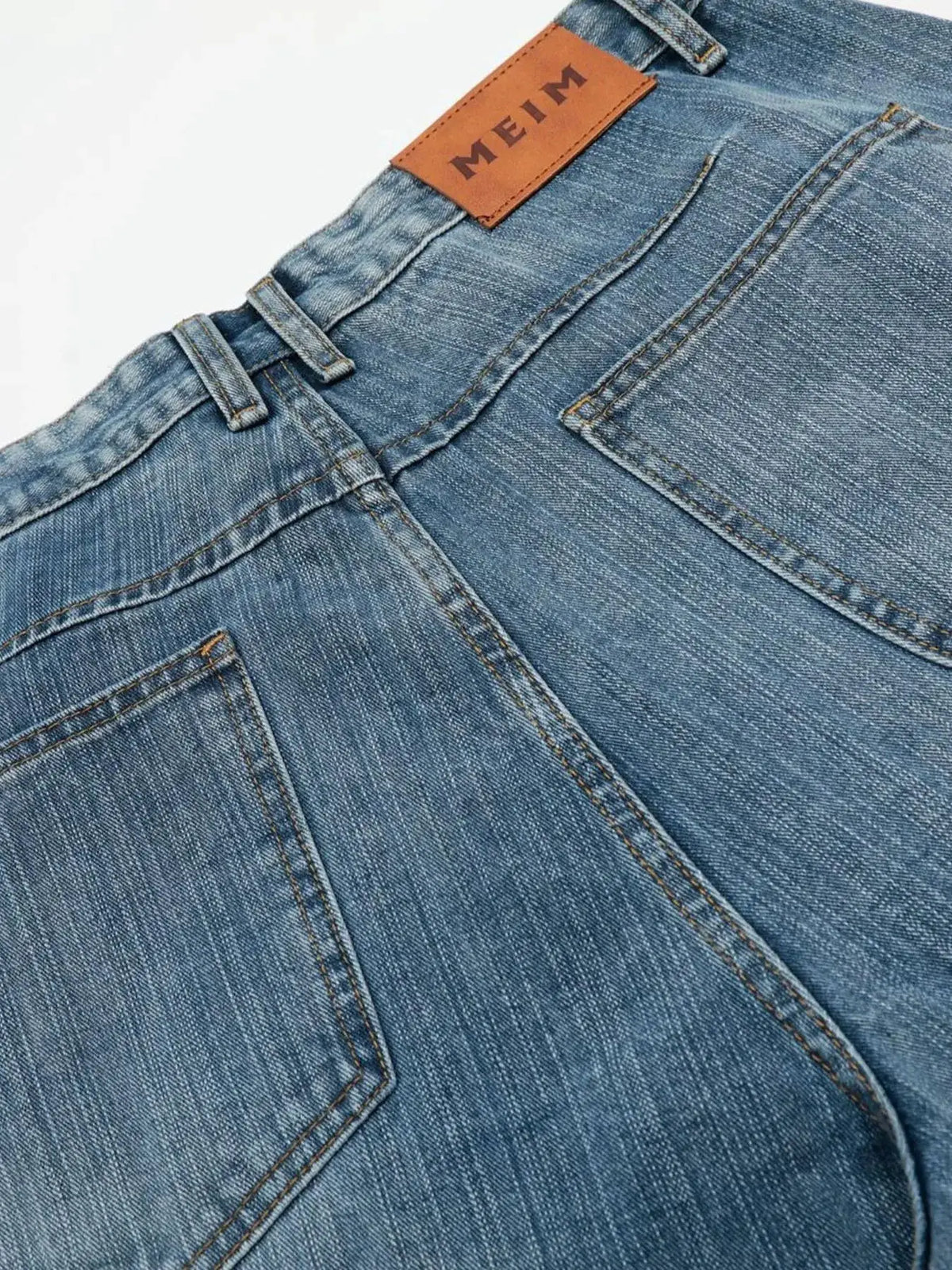 Men's blue denim shorts with belt loops and back pocket; brown leather patch visible