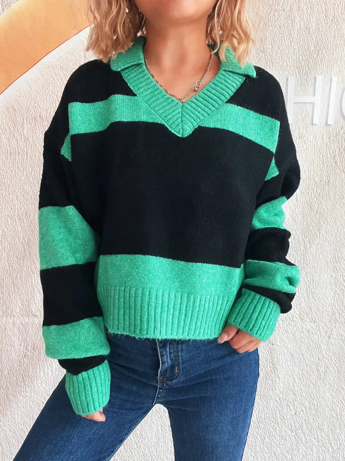 Color-block long-sleeve knit sweater in black and emerald green with ribbed V-neck collar; soft stretch polyester blend