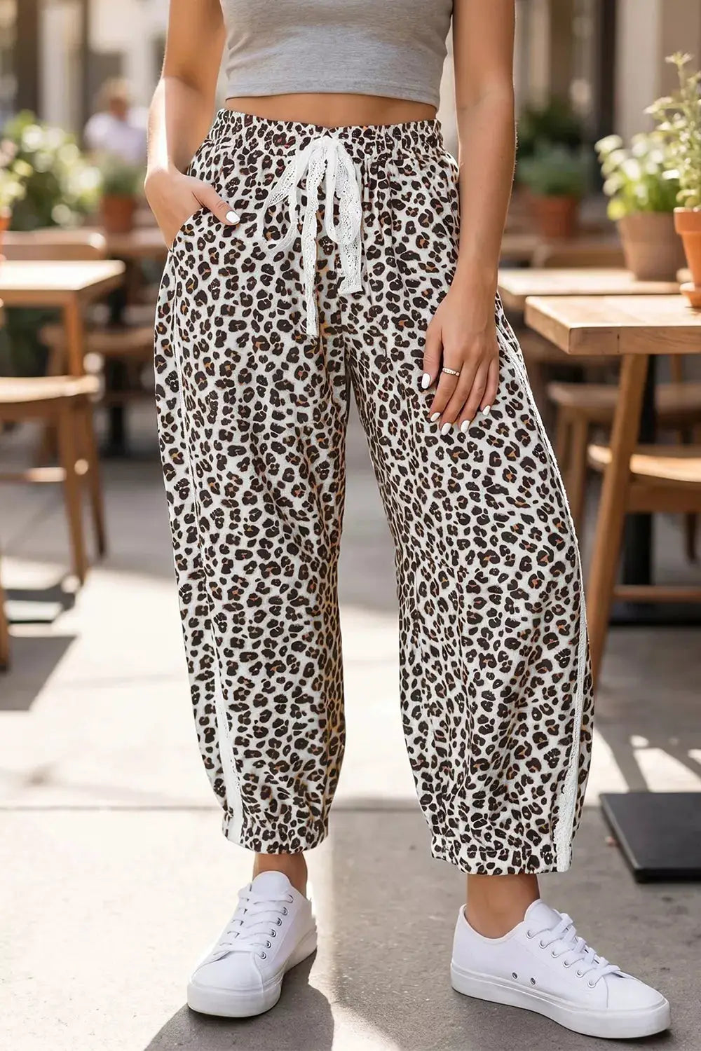 Leopard print ankle-length pants with elastic waist, white drawstring, and white side stripe.