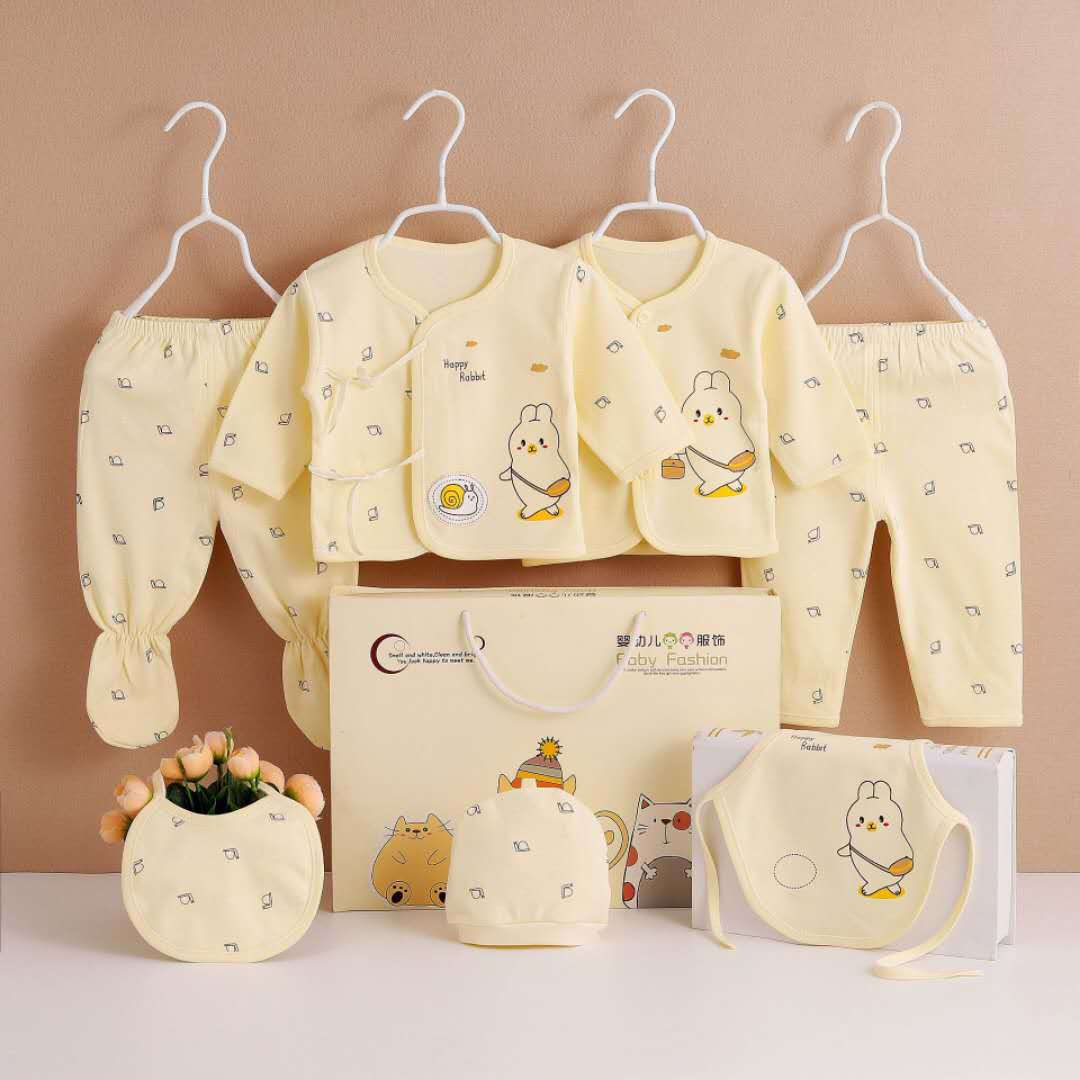 Seven-piece newborn clothing set in pale yellow by AdTec; includes hats, bibs, and outfits.