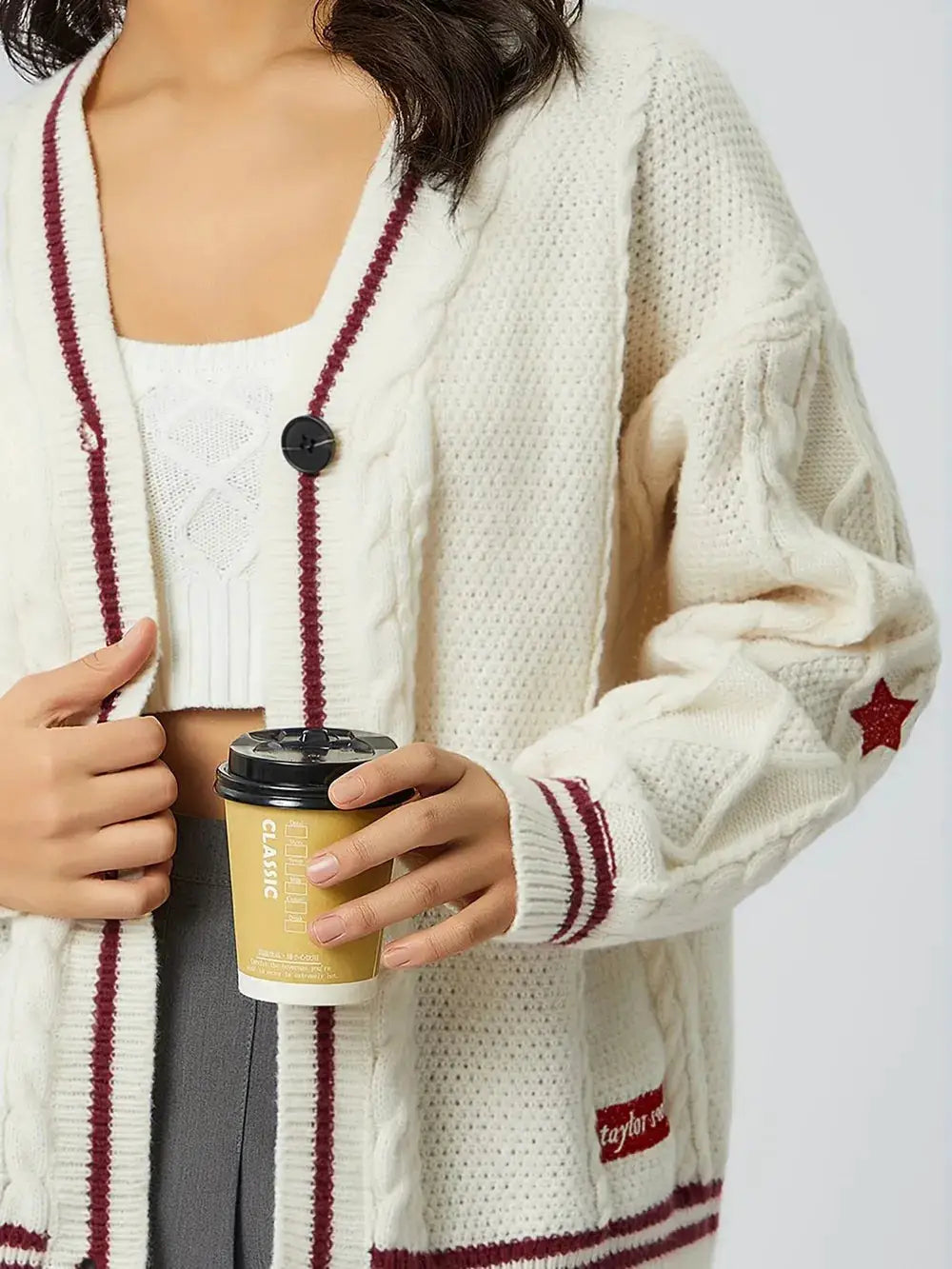 Womens star-embroidered cream knit cardigan with burgundy trim, V-neck, long sleeves, and button front.