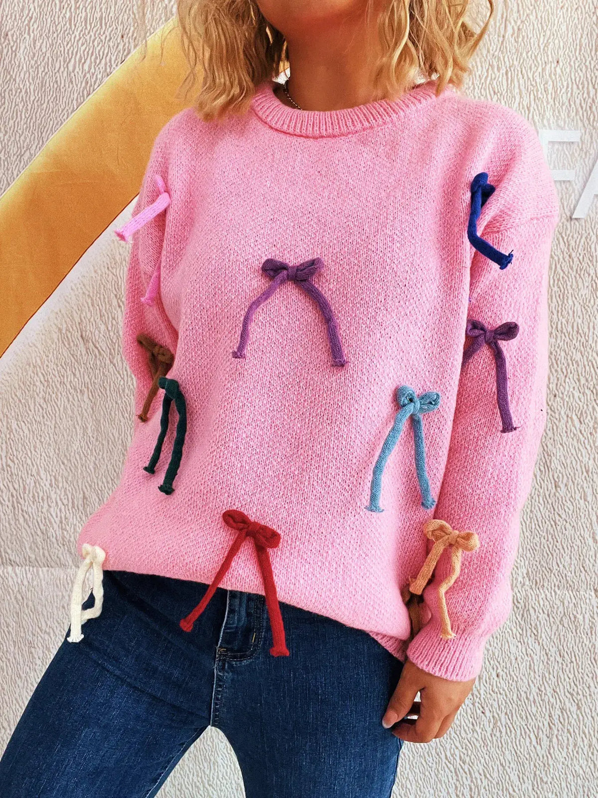 Vibrant bow-accent round-neck pullover sweater; pink fuzzy knit with multicolor bows on sleeves