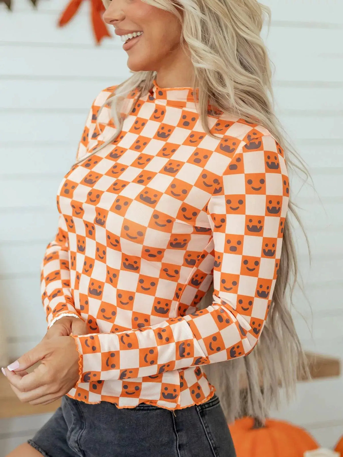 Trendsi abstract Halloween pattern long sleeve mock-neck blouse in orange and white checker with smiley faces.
