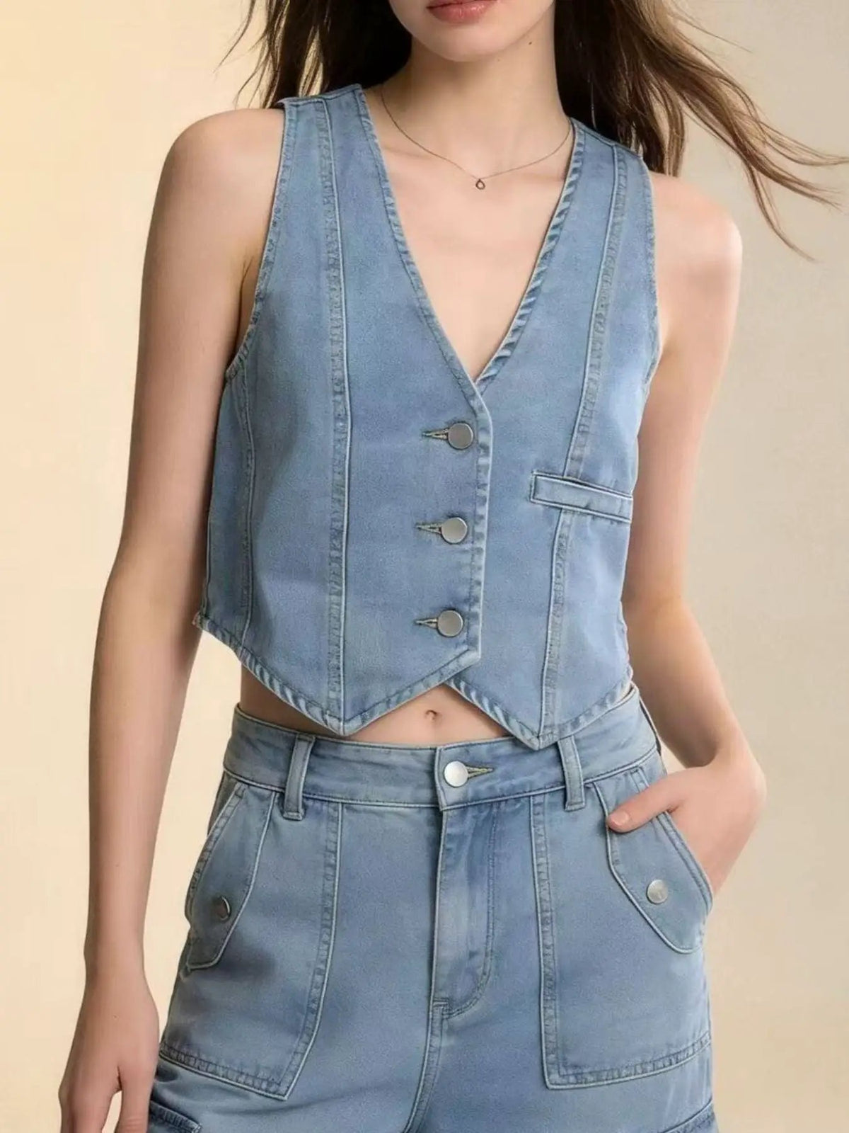 Unlined denim vest in light blue with front button closure, cropped fit.