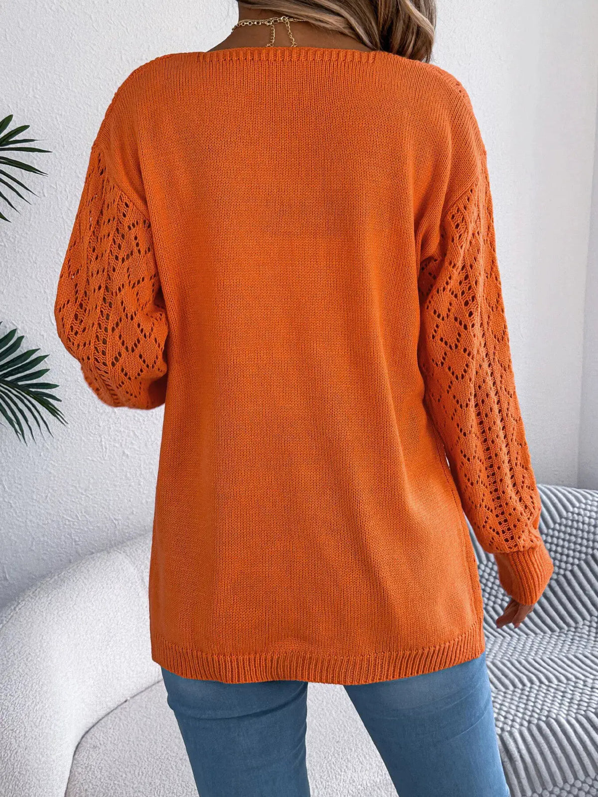 Openwork long sleeve cardigan in orange, back view with lace-pattern sleeves and ribbed hem