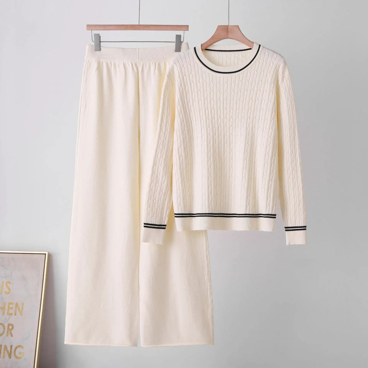 Long sleeve cable-knit two-piece lounge set by eprolo; ivory sweater with black-trim round-neck and matching pants