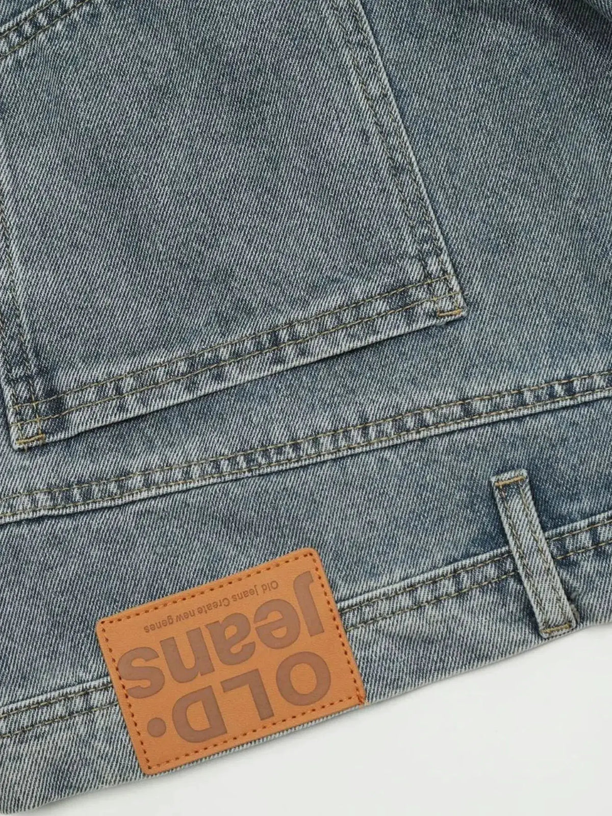 Men's washed blue denim shorts with back pocket stitching and orange leather patch.