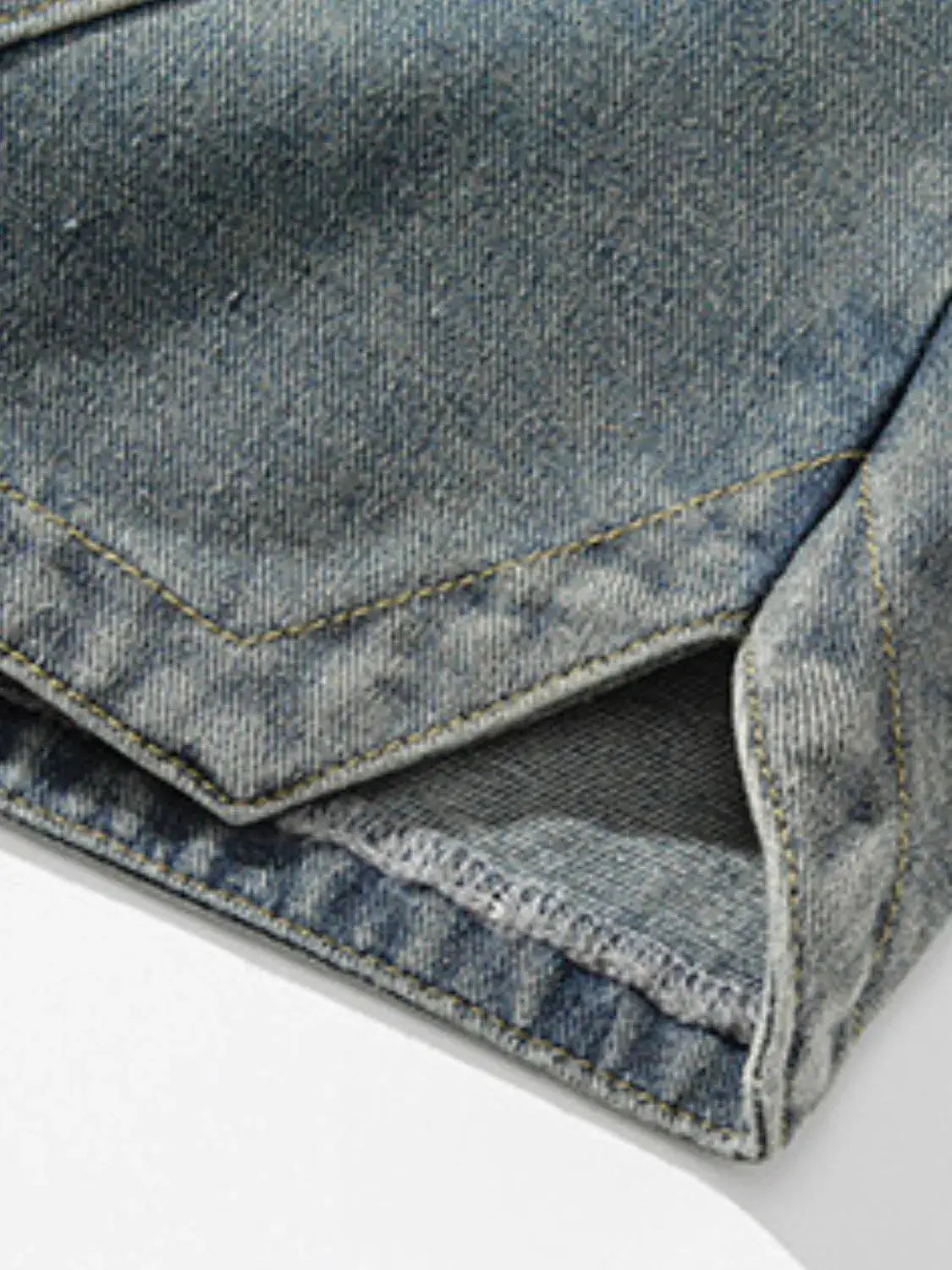 Mens plus-size cotton denim shorts; close-up of blue fabric with yellow topstitching and folded hem.