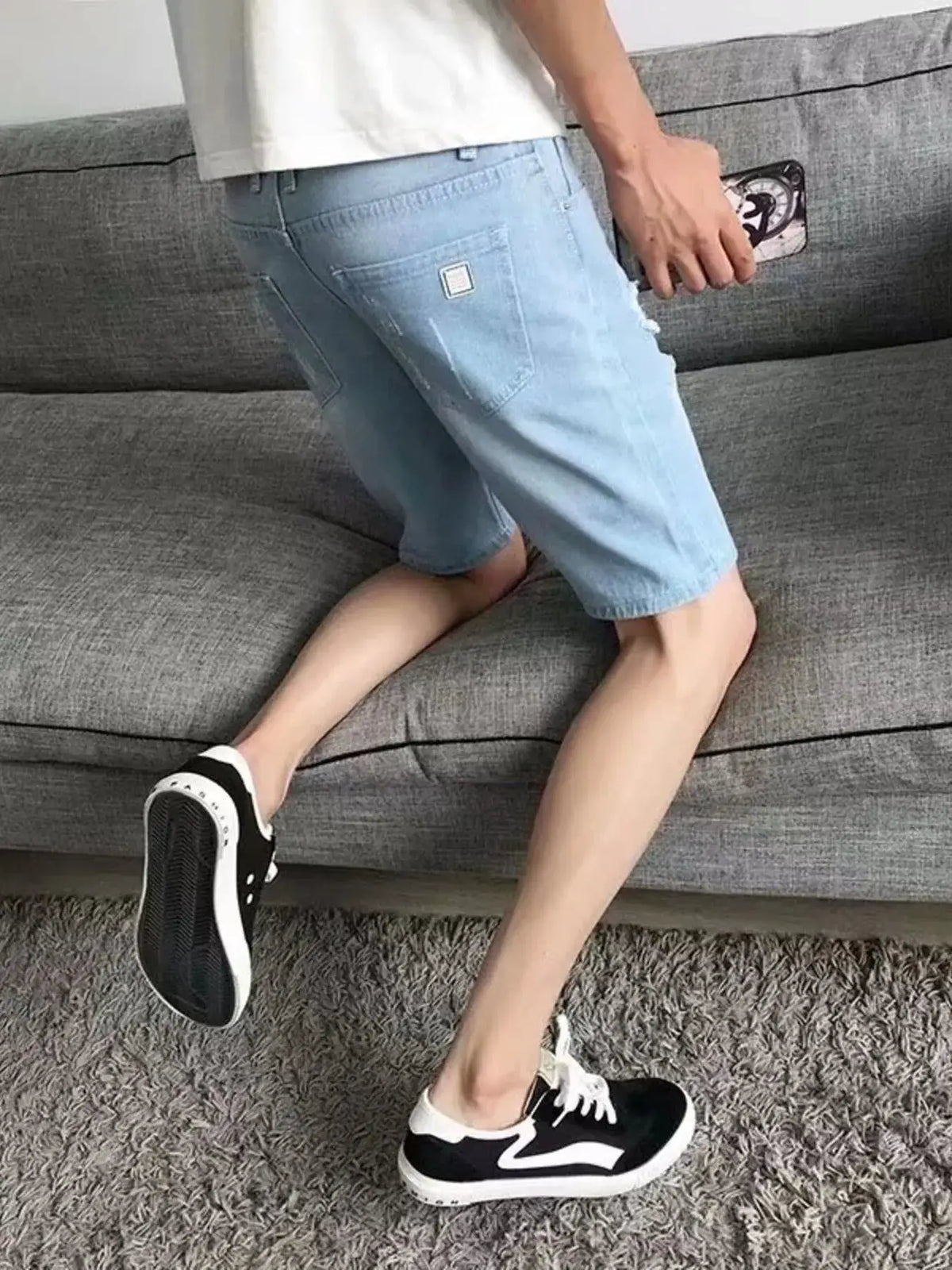 Men's relaxed-fit distressed wash vintage denim shorts in light blue with ripped knee detail