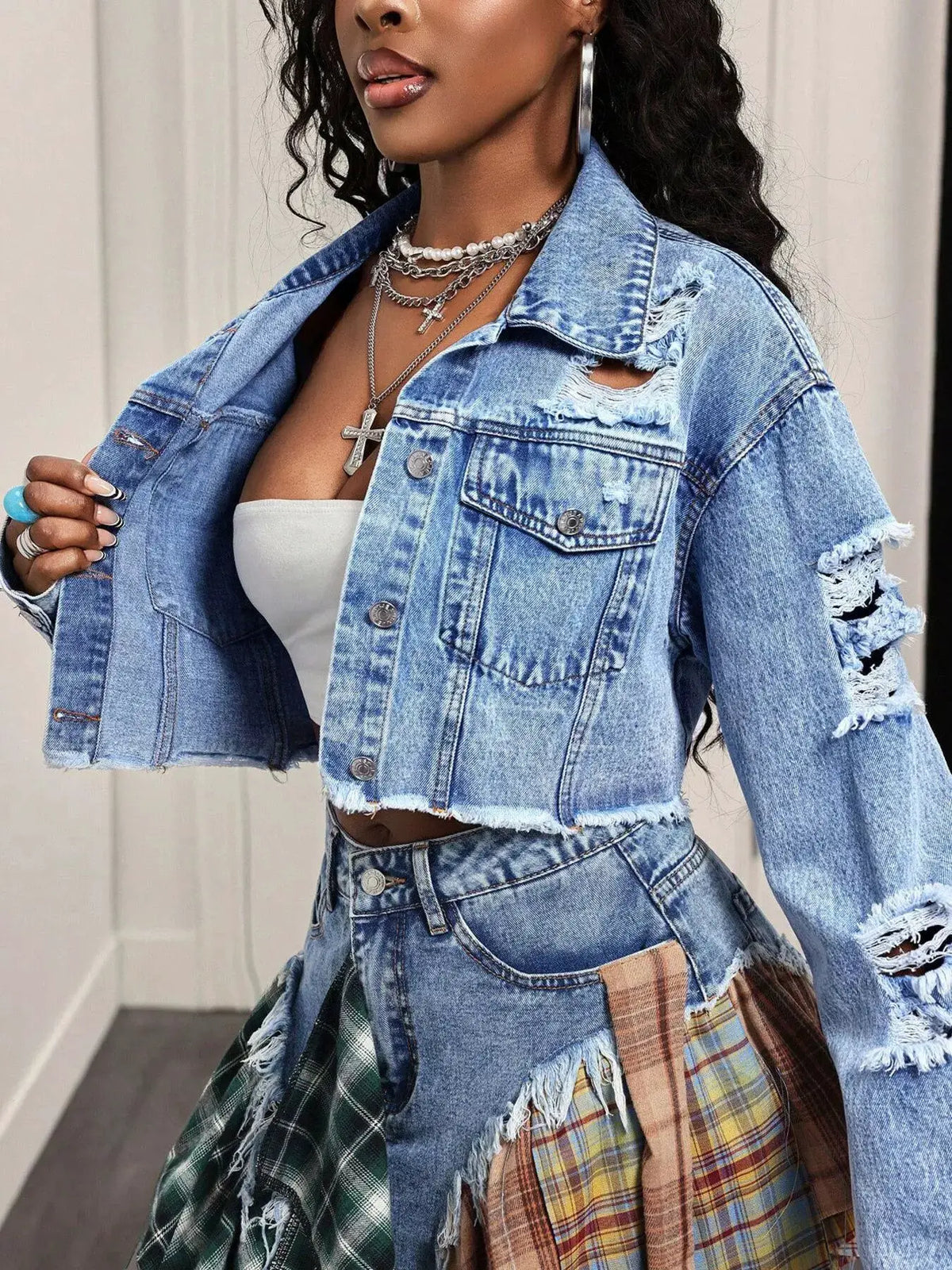 Distressed cropped denim jacket with an asymmetrical hem in light wash, featuring ripped sleeves.