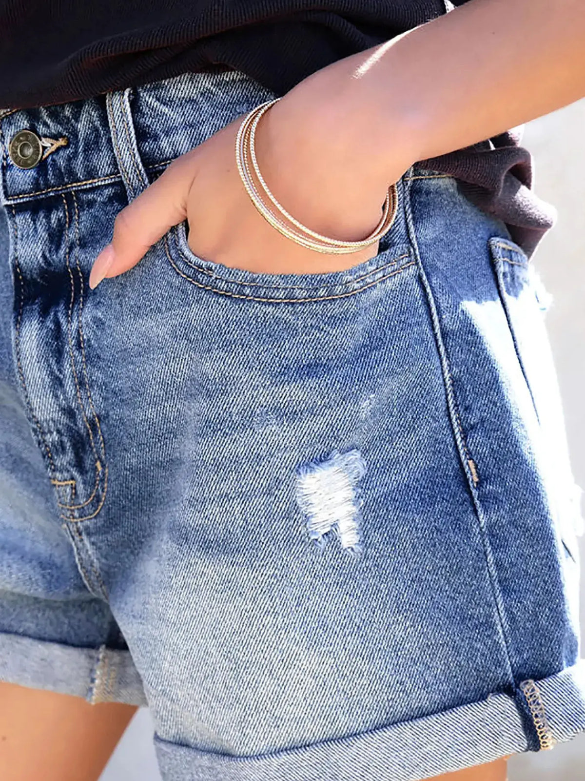 Distressed denim shorts with relaxed fit and cat whisker wash, light blue with cuffed hem.