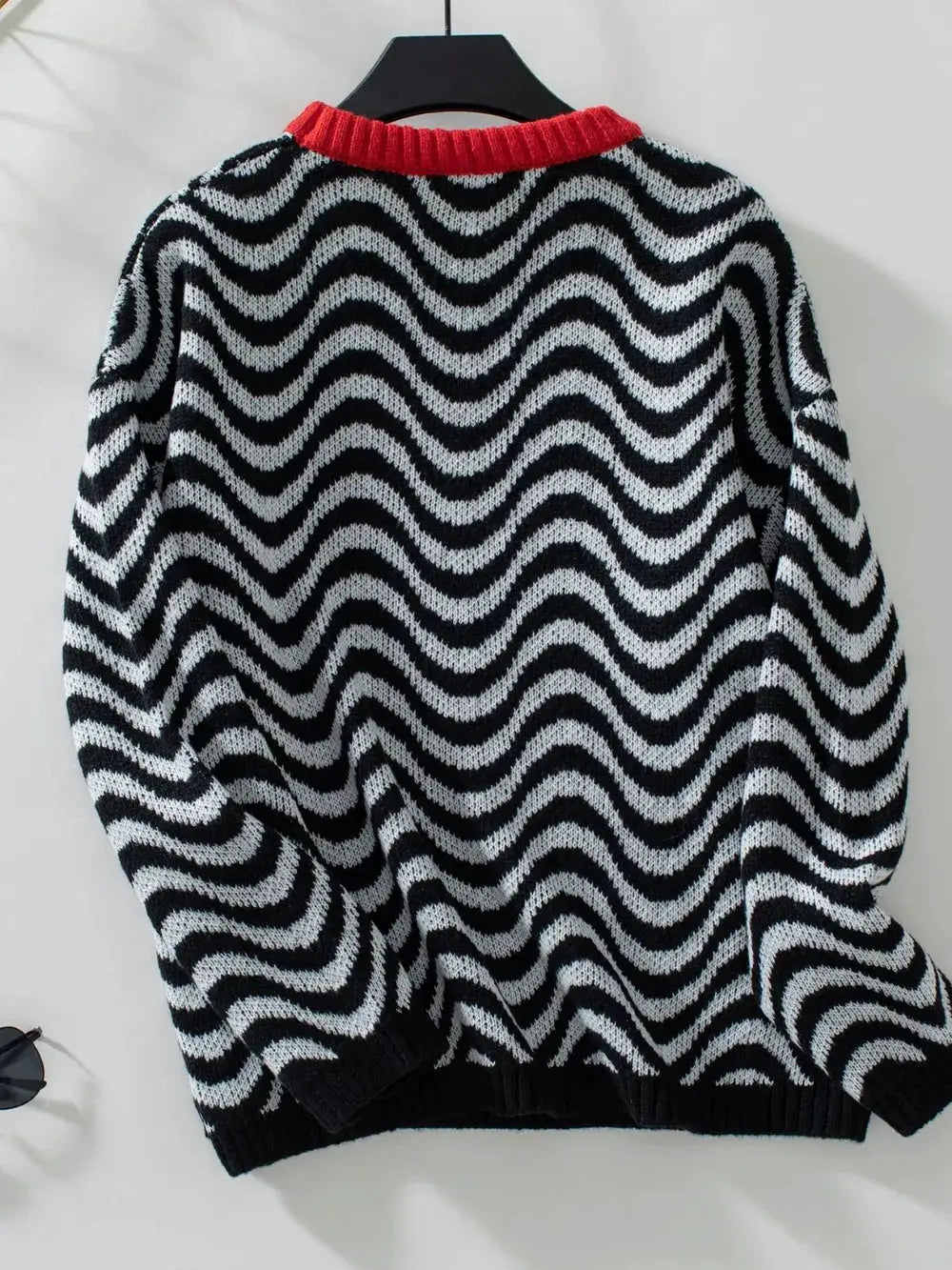 Casual wavy stripe knit sweater with black and white pattern and red ribbed crew neck, long sleeves