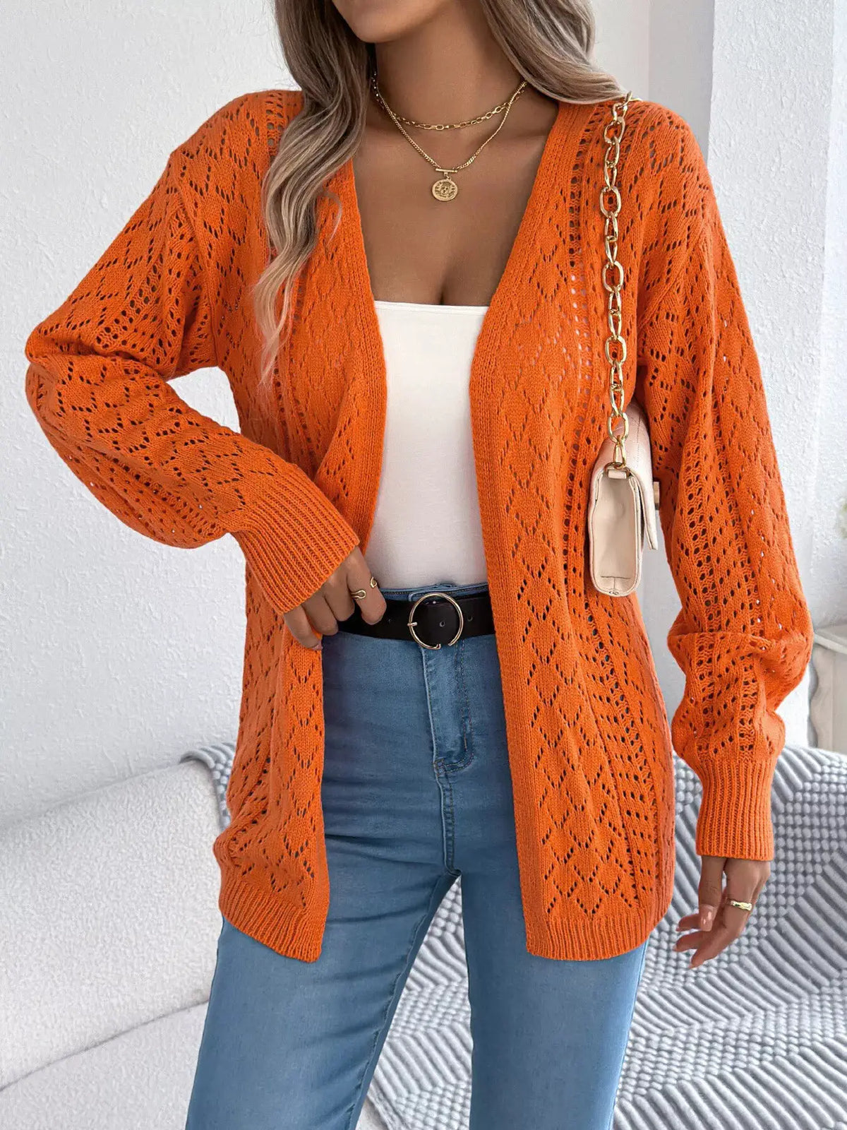 Openwork orange long-sleeve cardigan; open-front stretch knit, Trendsi, worn over white top with blue jeans.