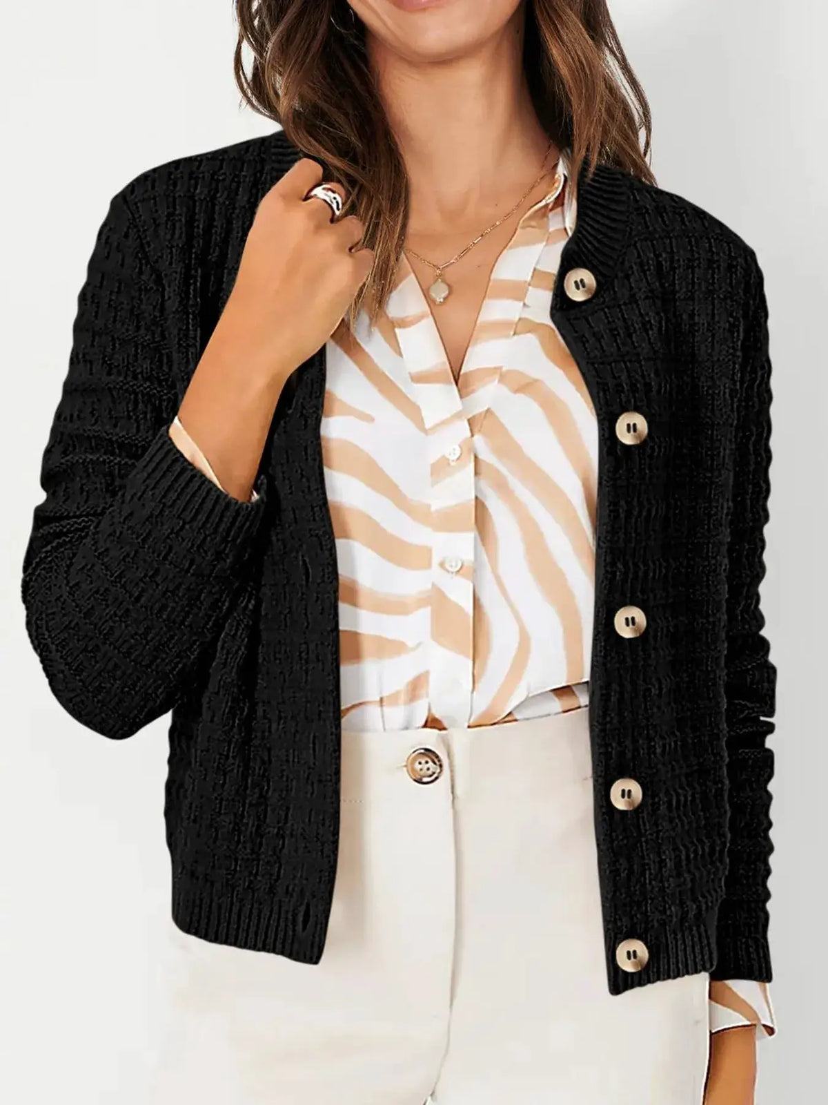 Textured stretchy knit button-front cardigan in black, with beige-striped blouse and cream trousers, three-piece outfit