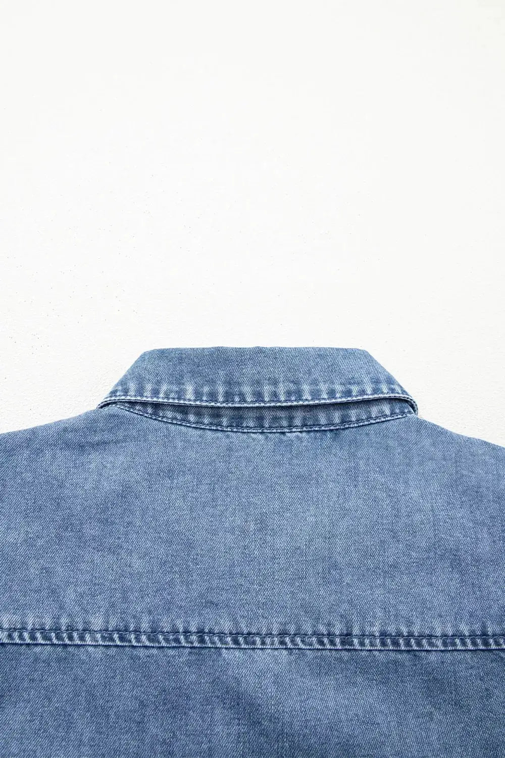 Denim shirt with a structured collar in blue wash, back view.