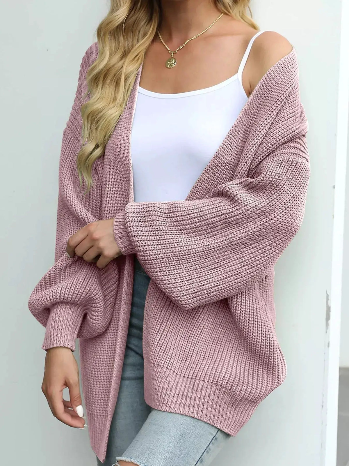 Pink oversized chunky knit cardigan with open front and stretchy fabric worn over a white tank.