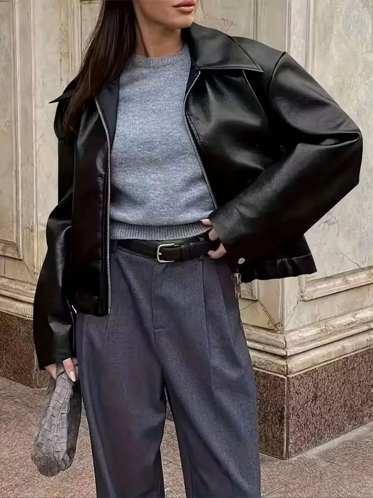 Oversized faux leather moto jacket with full-zip front in black, shown over a gray knit sweater.